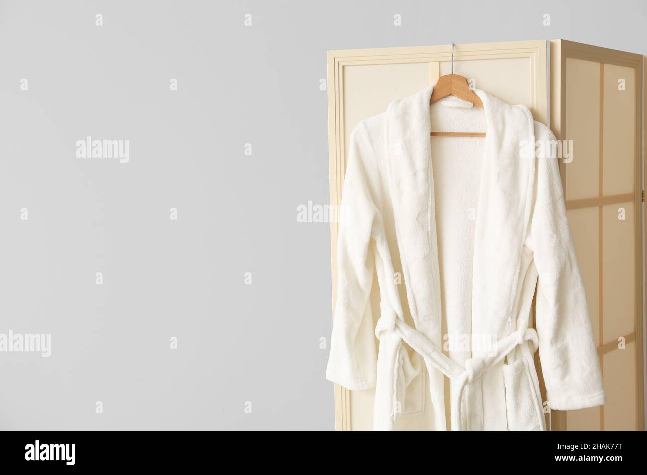 Folding screen with bathrobe near light wall Stock Photo Alamy