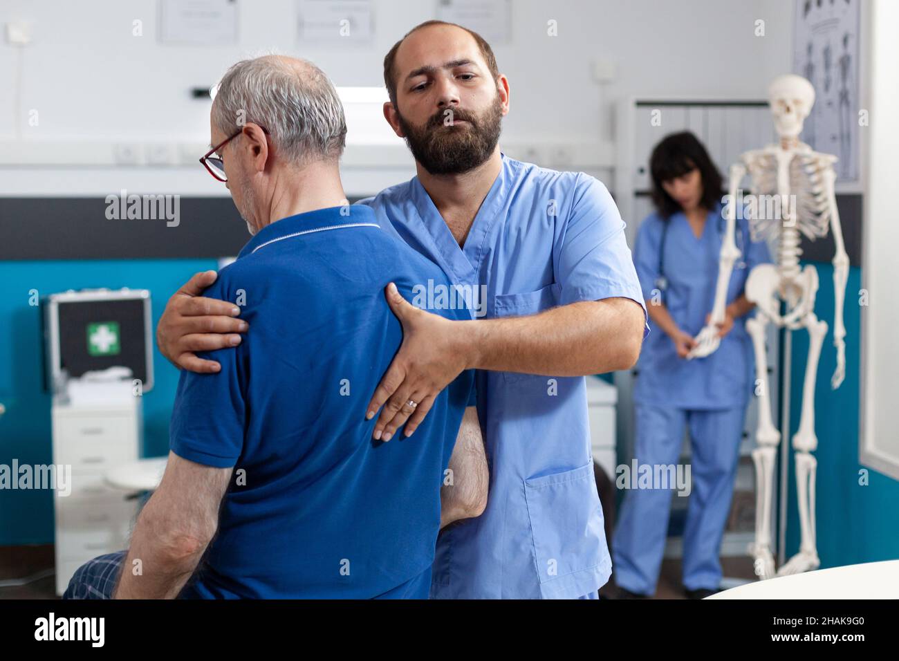 Orthopedic nurse stretching spinal cord and shoulder of elder patient with injury for