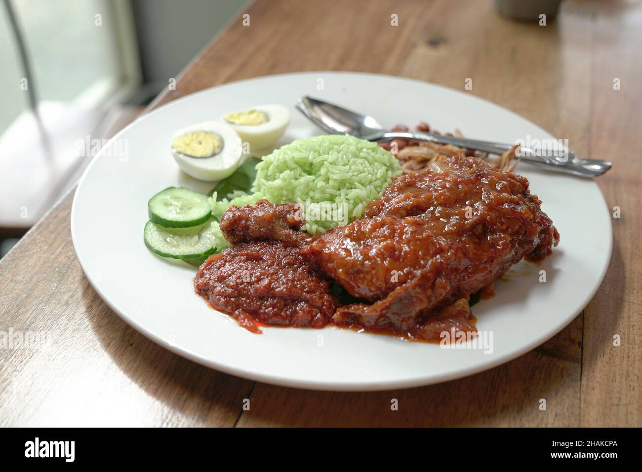 Nasi Lemak coconut rice with spicy fried chicken, boiled egg, curry, peanuts, anchovies and cucumbers. Ready to eat. Stock Photo