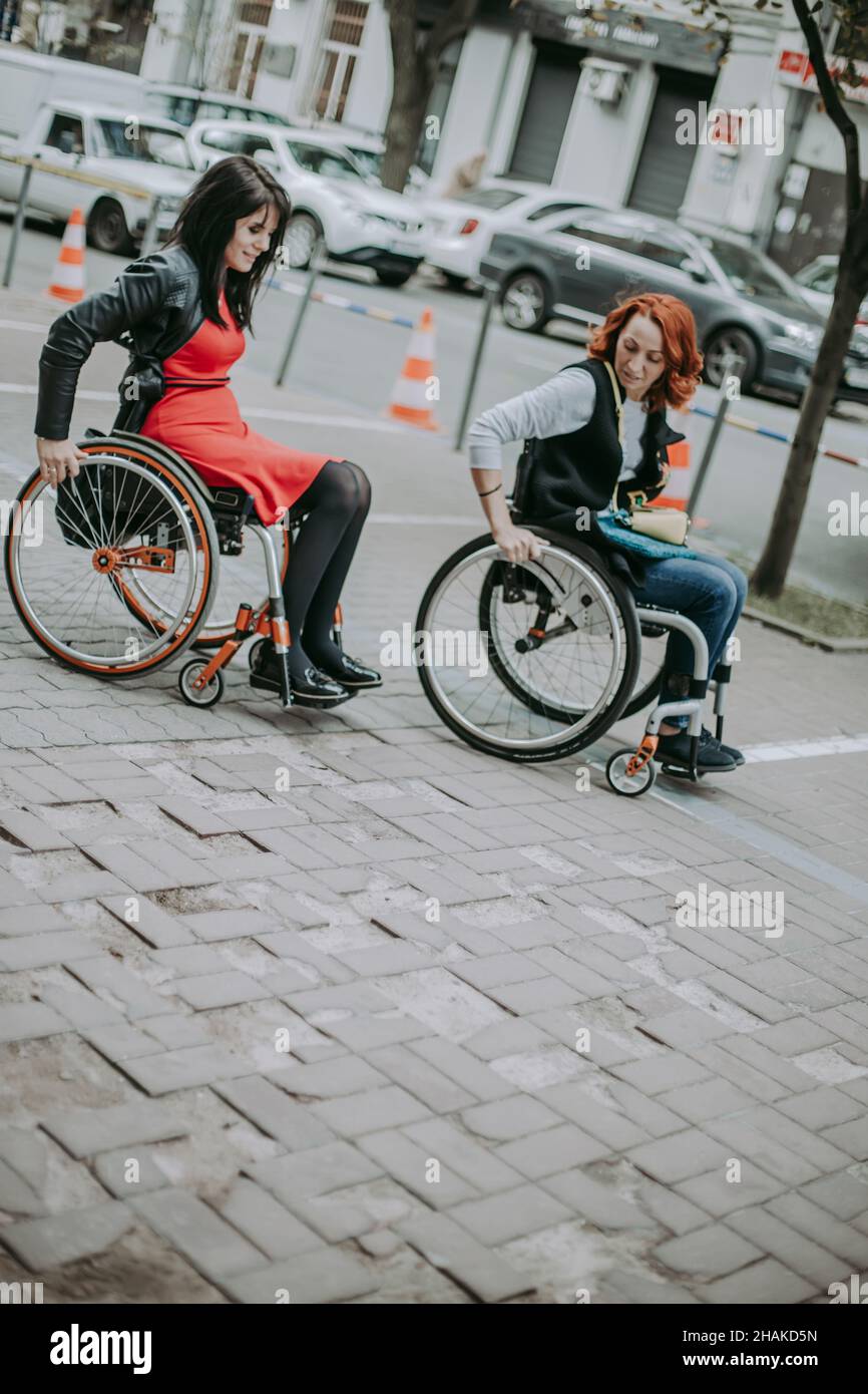 Two girls in wheelchairs travel through the central streets. Friends
