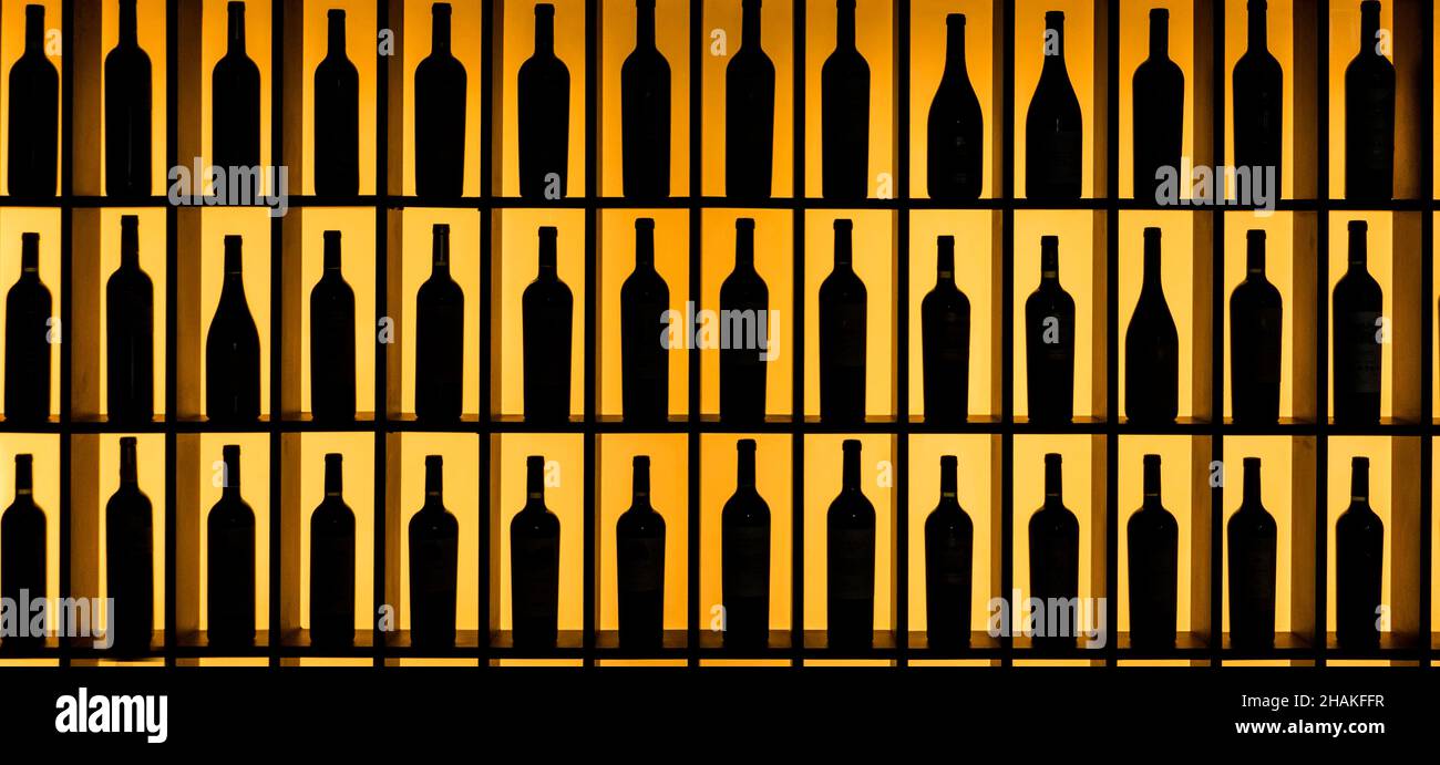 Wine bottles silhouetted on shelves Stock Photo