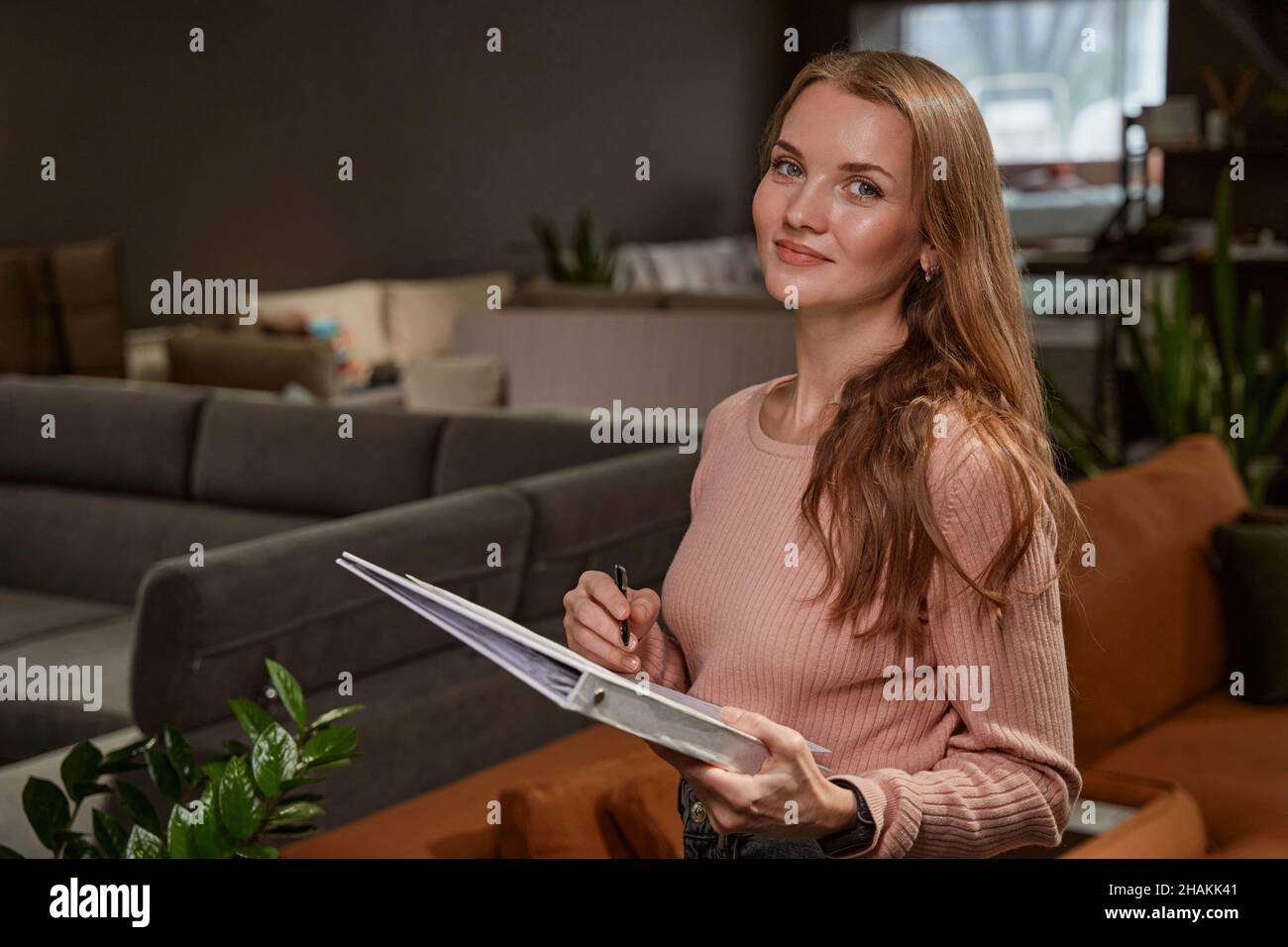 Happy lady with documents standing in furniture shop Stock Photo