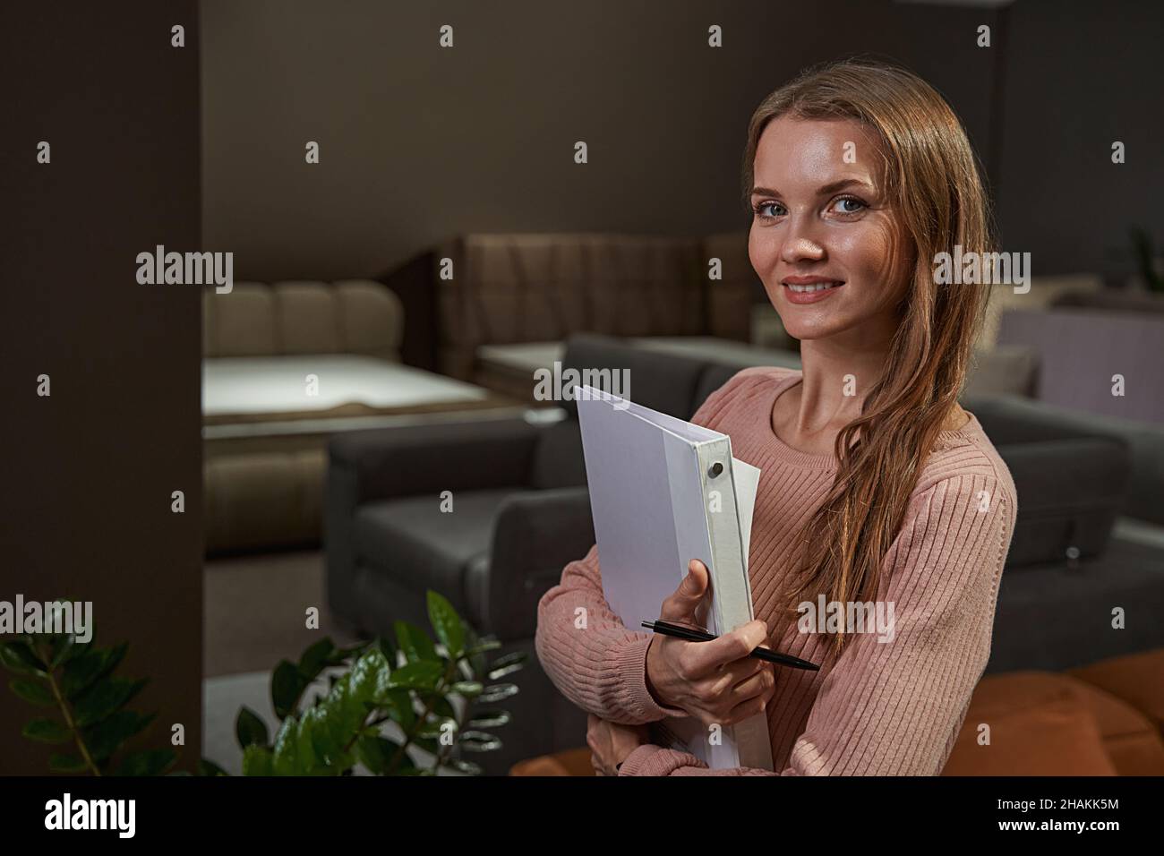 Smiling woman with documents standing in furniture shop Stock Photo