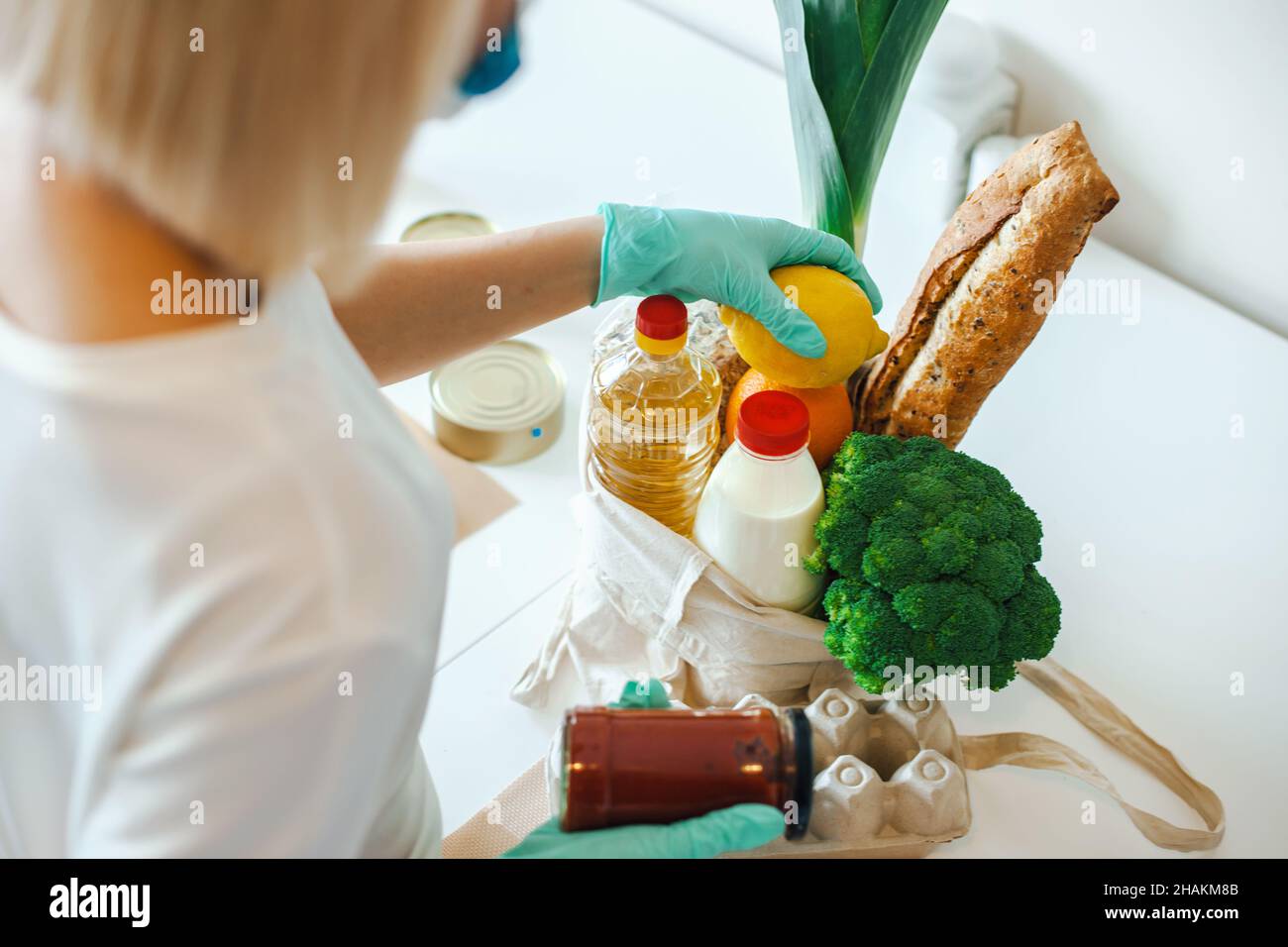 Back view of woman's hands wearing medical gloves packing food donation ...