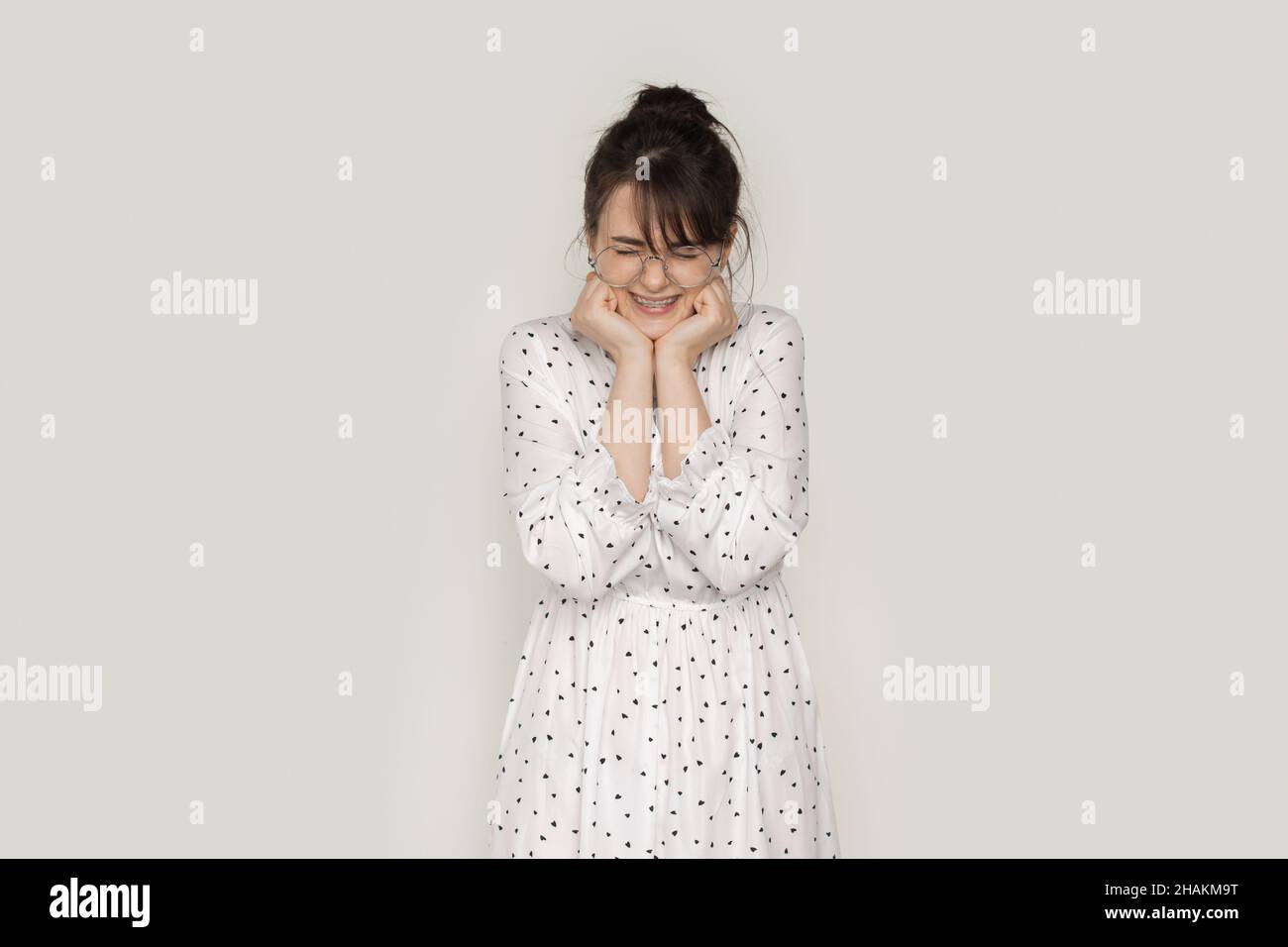 Portrait of an excited young woman screaming and holding her hands under chin isolated over white background Stock Photo