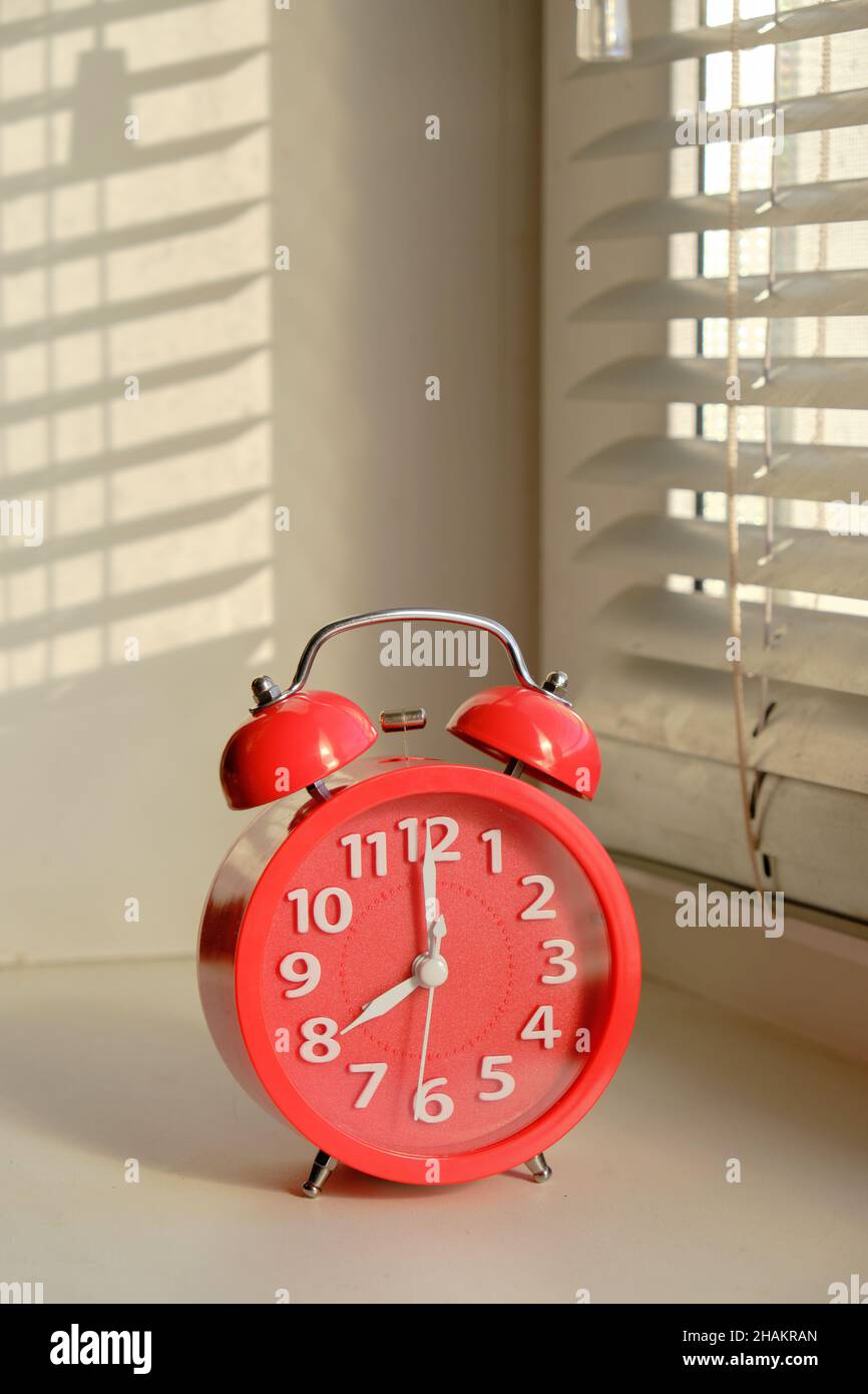 Red alarm clock early morning windowsill in rays sun Stock Photo Alamy