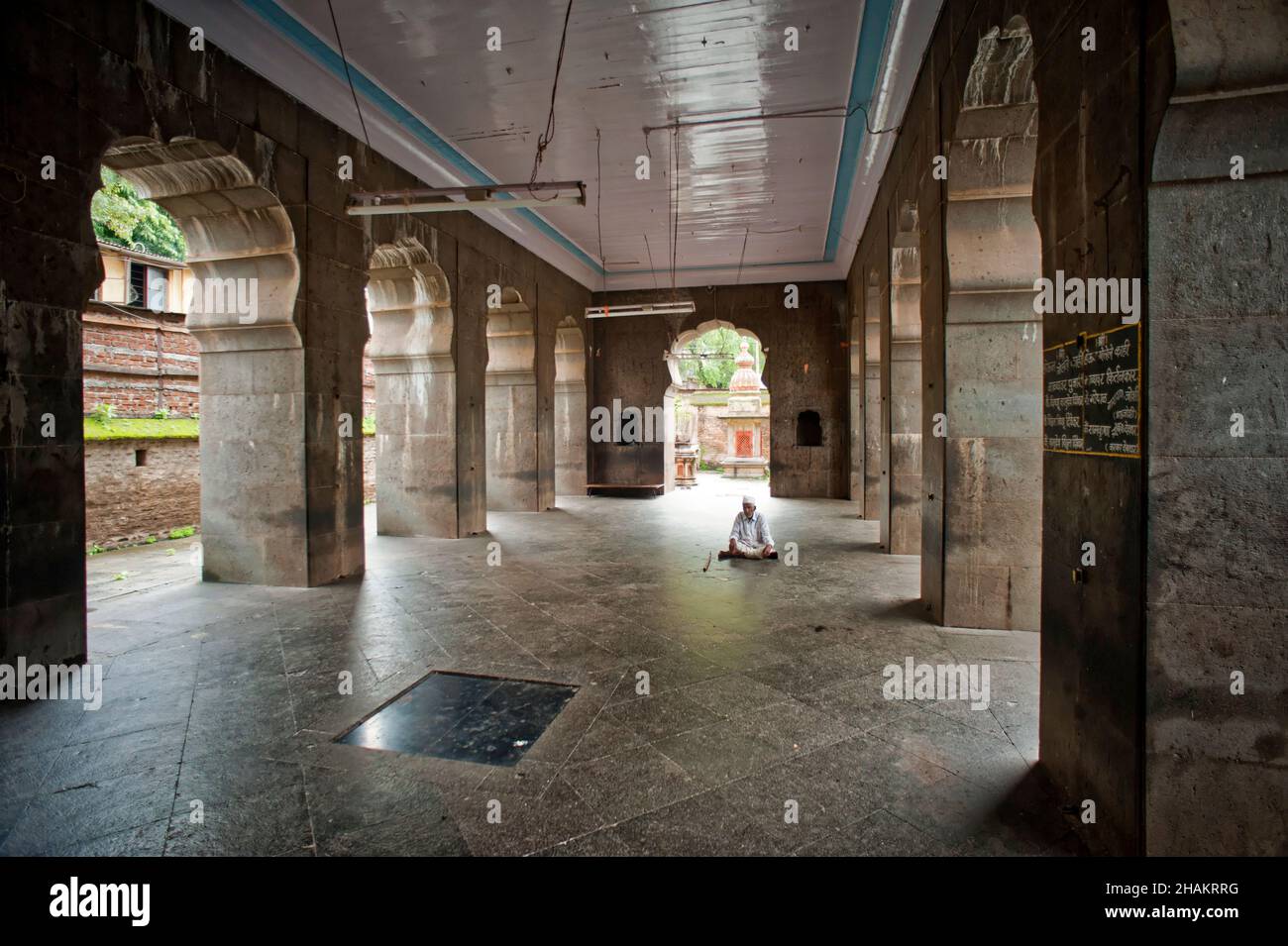 Big and naturally lighted hall and pillars of Shri Vishnu Mandir Hindu temple and a worshiper Stock Photo