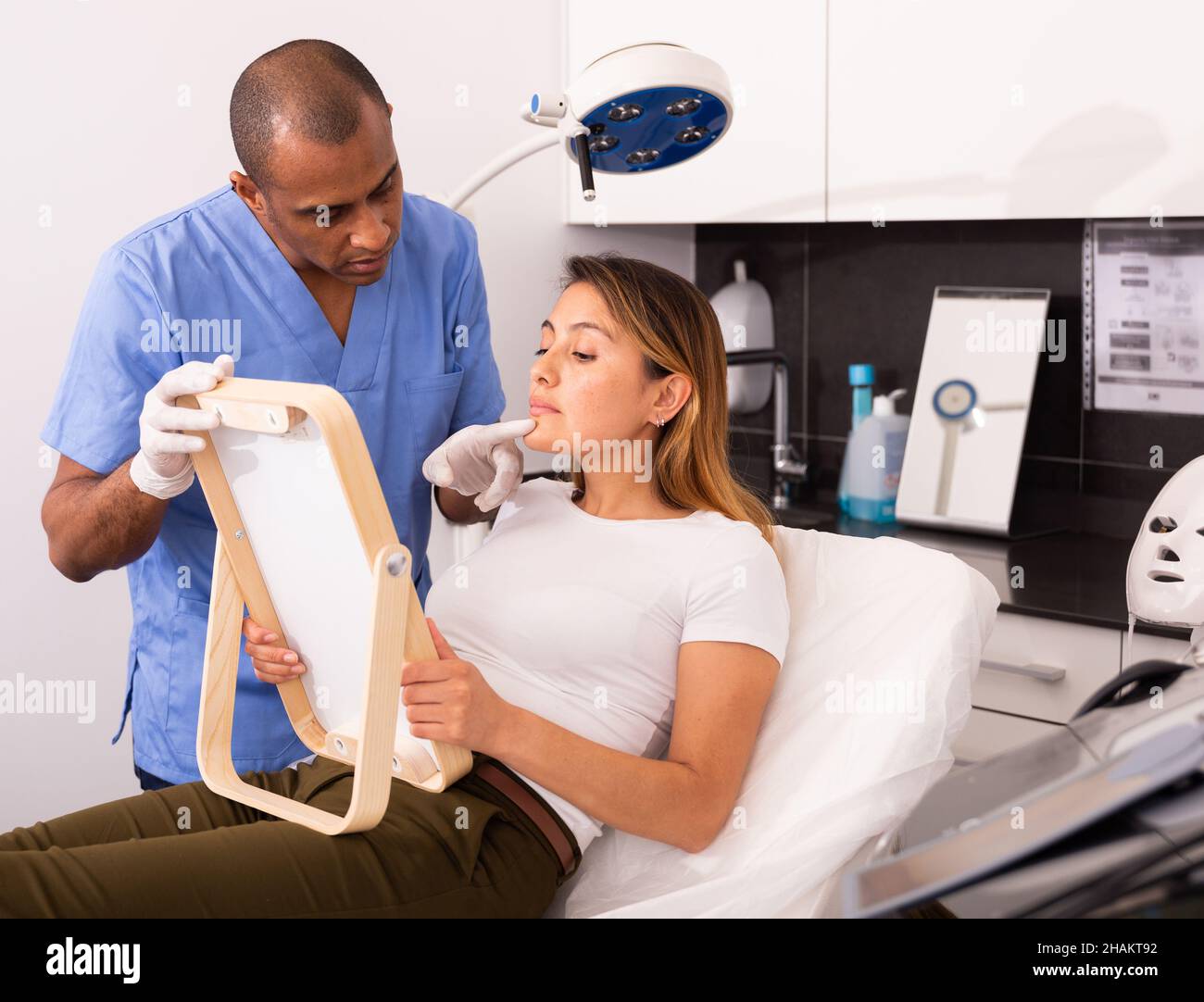 Beautician explaining woman hardware facial procedure Stock Photo - Alamy