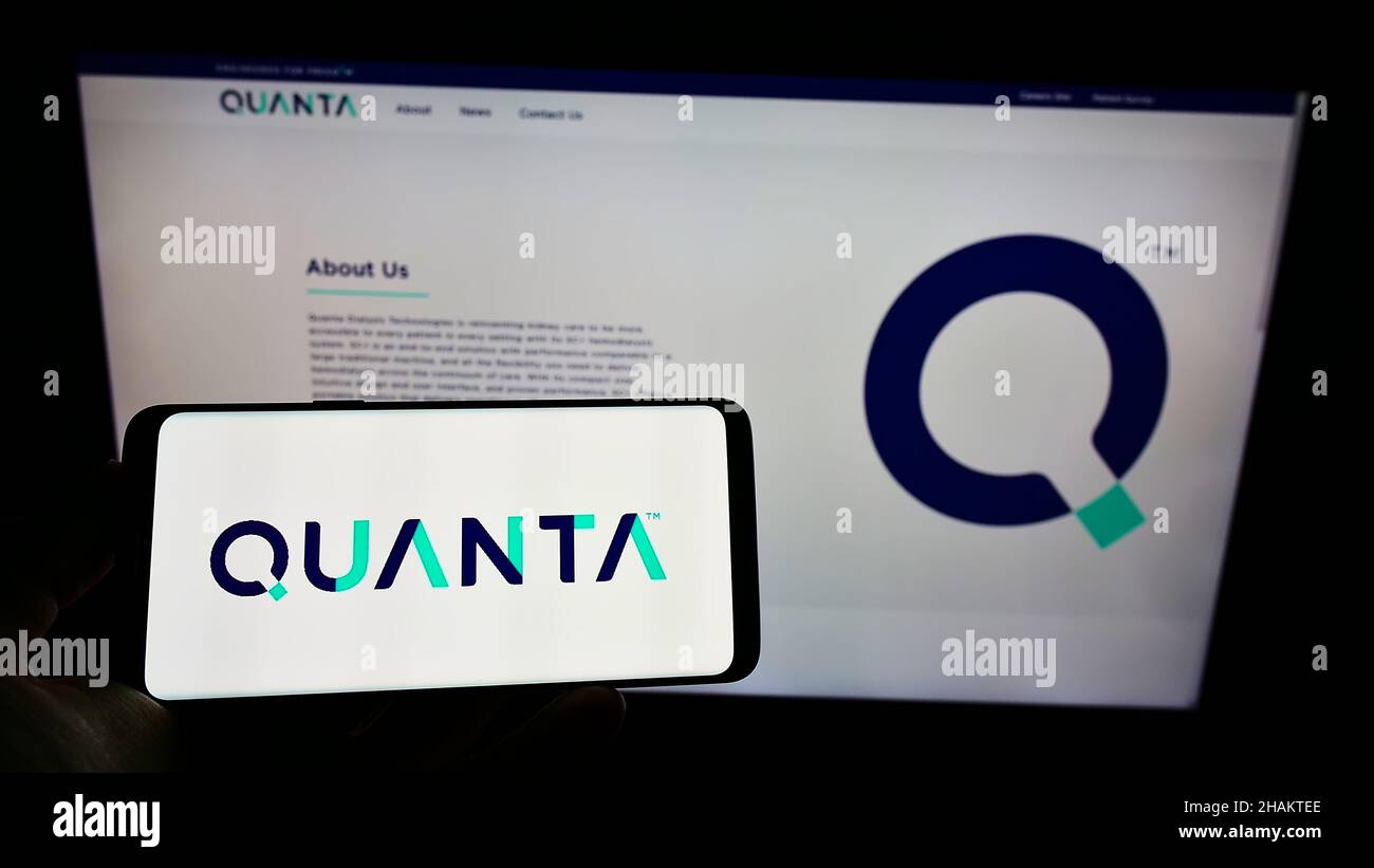 Person holding smartphone with logo of British company Quanta Dialysis Technologies Limited on screen in front of website. Focus on phone display. Stock Photo