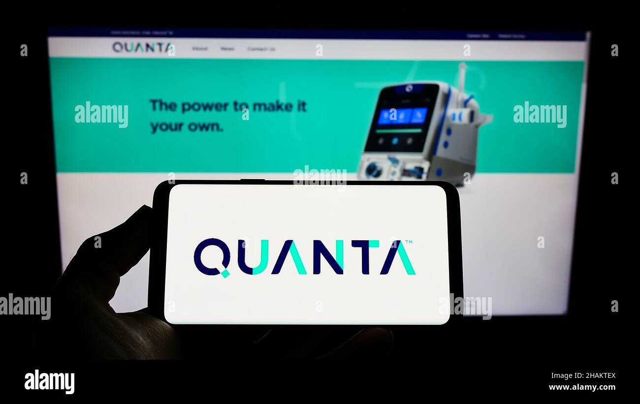 Person holding mobile phone with logo of company Quanta Dialysis Technologies Limited on screen in front of web page. Focus on phone display. Stock Photo