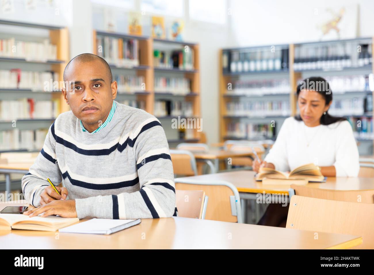 Latin American adult reading books in public library Stock Photo Alamy