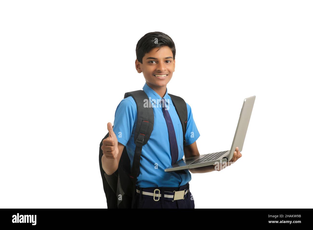 Indian school boy in uniform and using laptop on white background. Stock Photo