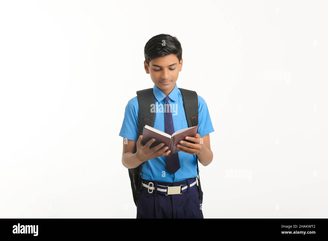Indian school boy in uniform and reading diary on white background. Stock Photo