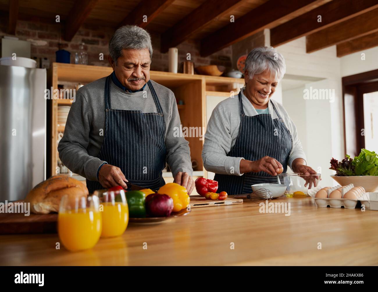 Happy multicultural elderly couple preparing meal in modern kitchen. Eating healthy food at