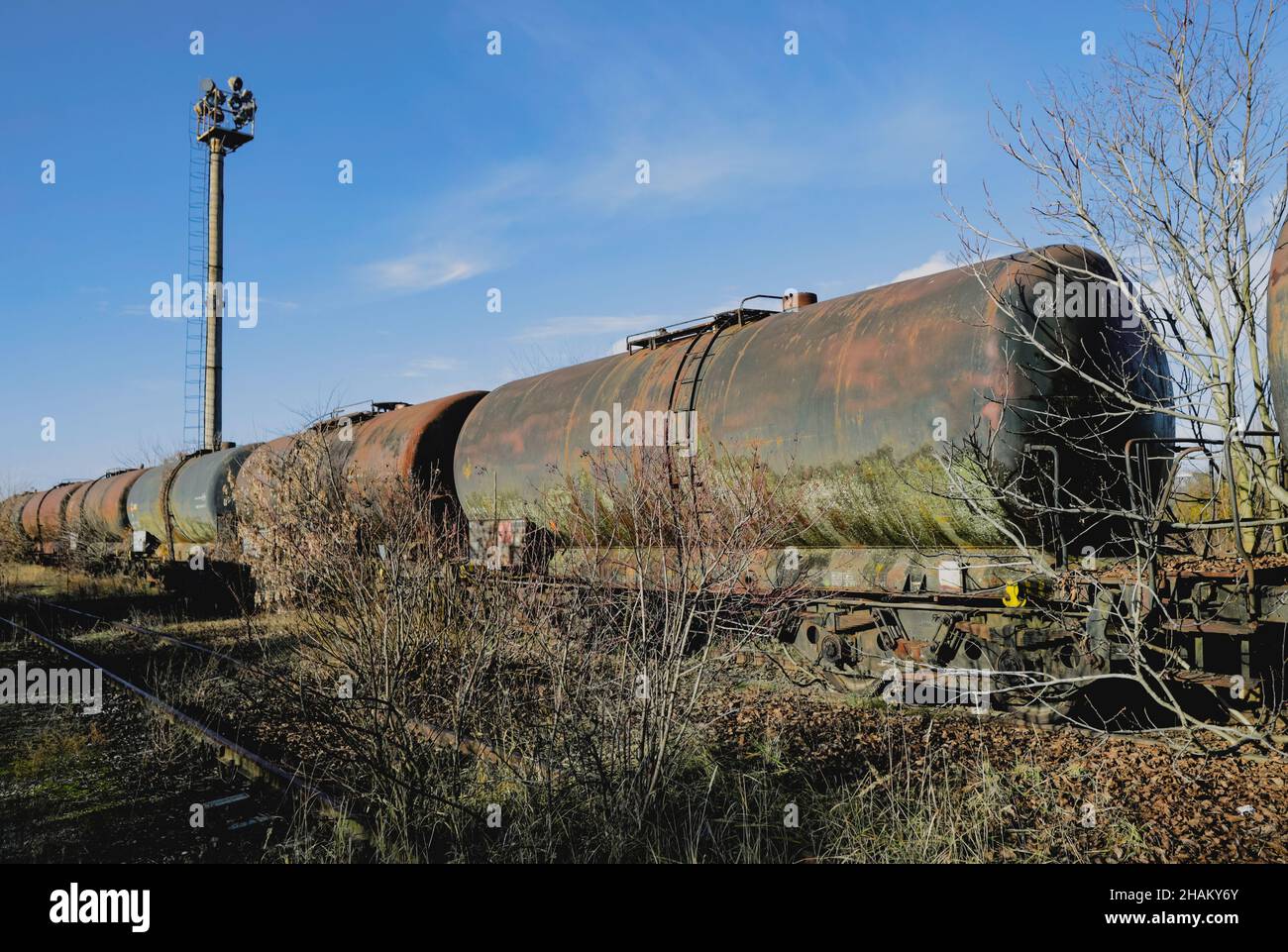 Shallow depth of field (selective focus) image with old and rusty railway oil tankers in the middle of a field on a sunny winter day. Stock Photo