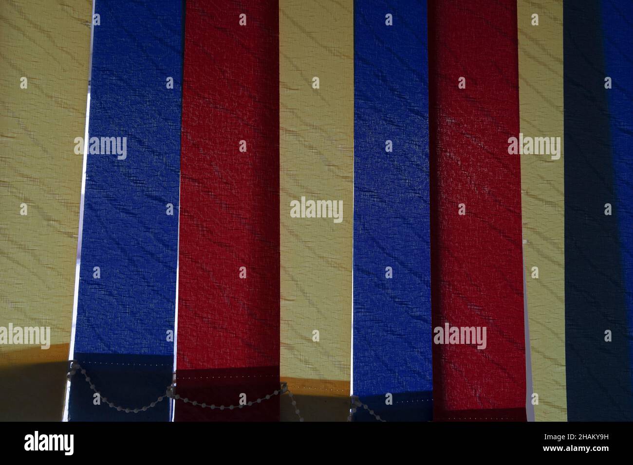 Vertical fabric blinds of blue, yellow and red colors installed on the