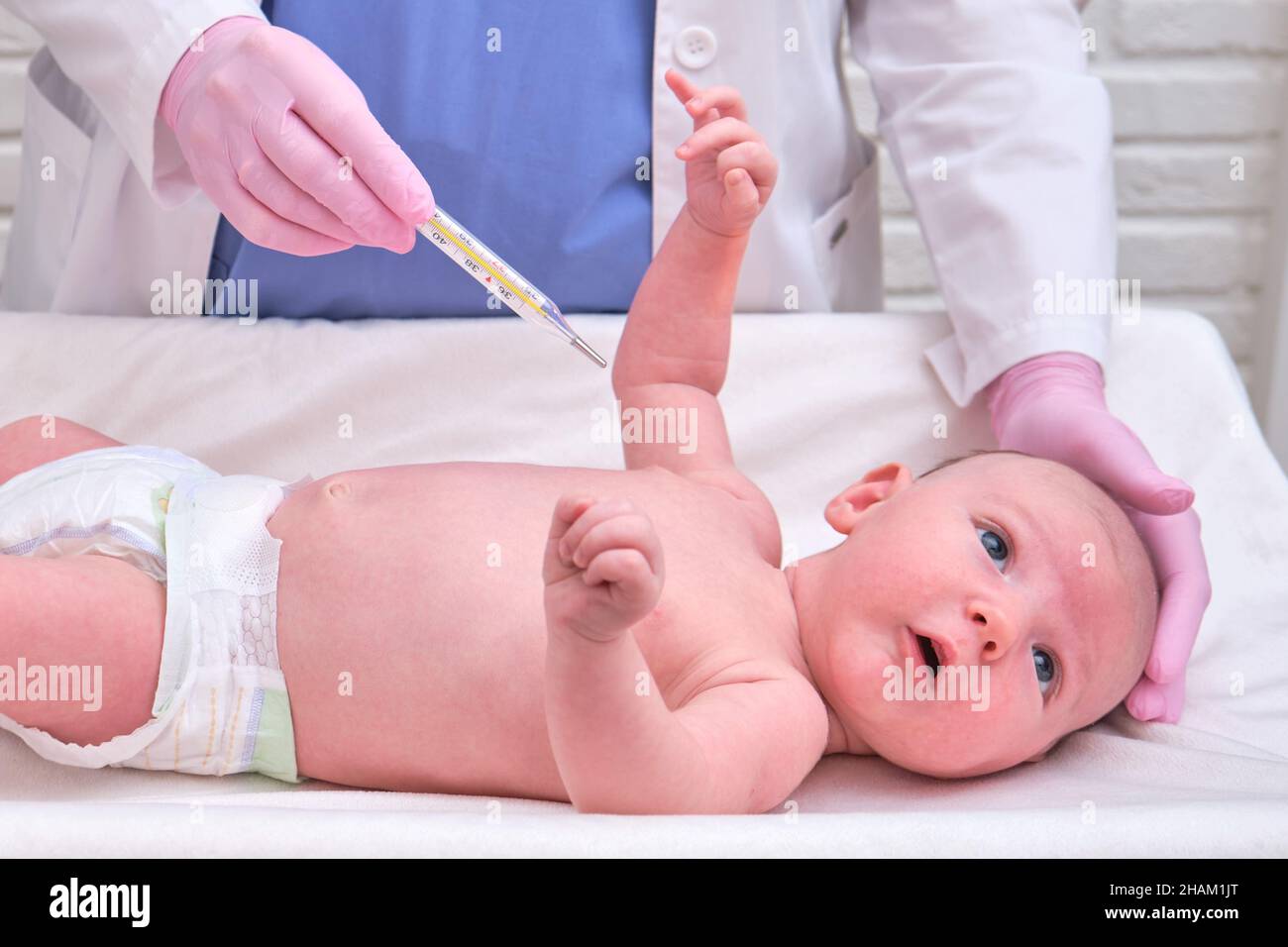 Doctor checks the temperature of the newborn baby with a thermometer. A