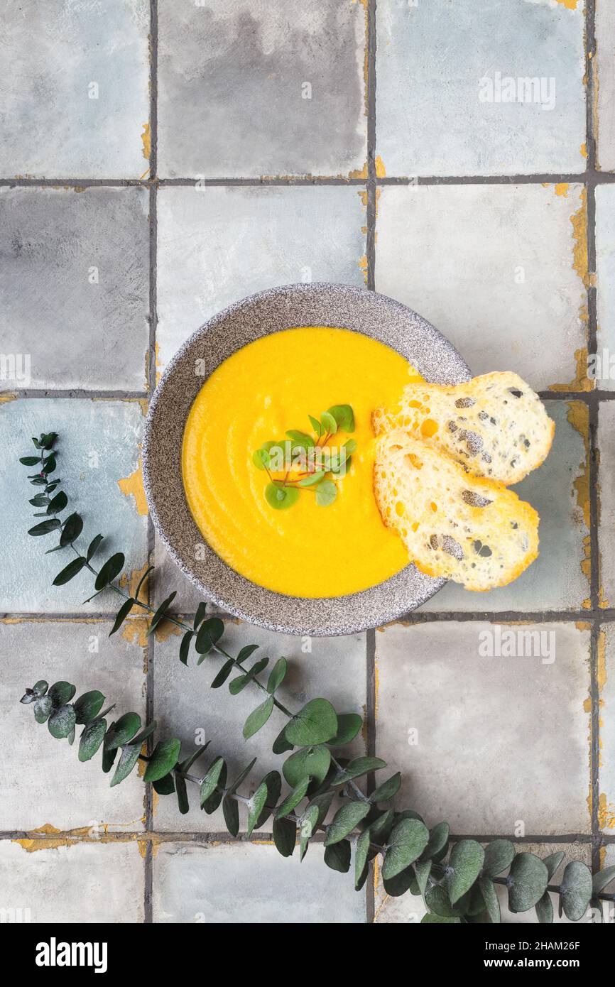 Pumpkin and carrot cream soup on white tile background with croutons ...