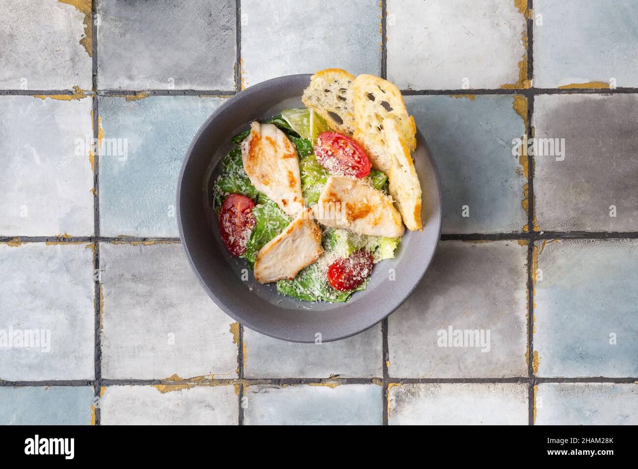 Healthy organic Chicken Caesar Salad with grilled chicken and croutons on tile background Stock Photo