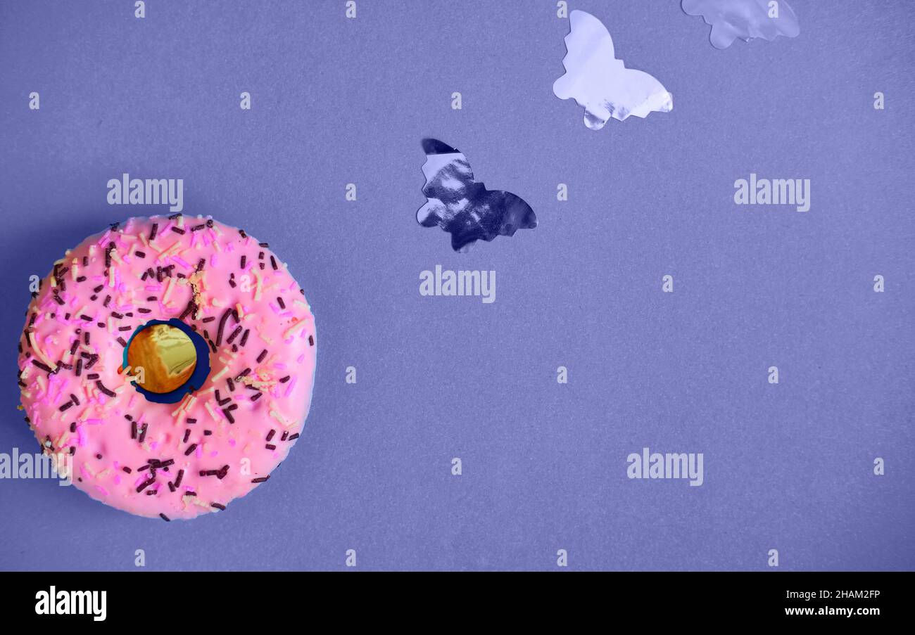 Pink sweet donut on a lilac background with small butterflies. Color of the year very peri Stock Photo