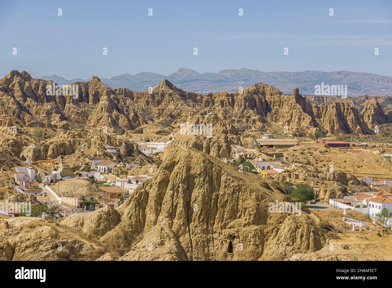 The cave house quarter with troglodyte habitations to protect from the heat in Guadix. The heat causes a blurry view for the distant mountains. Stock Photo
