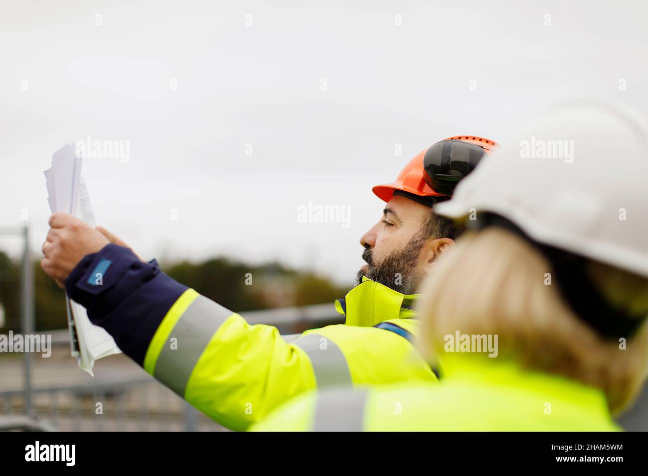 Engineers in reflective clothing discussing plans Stock Photo