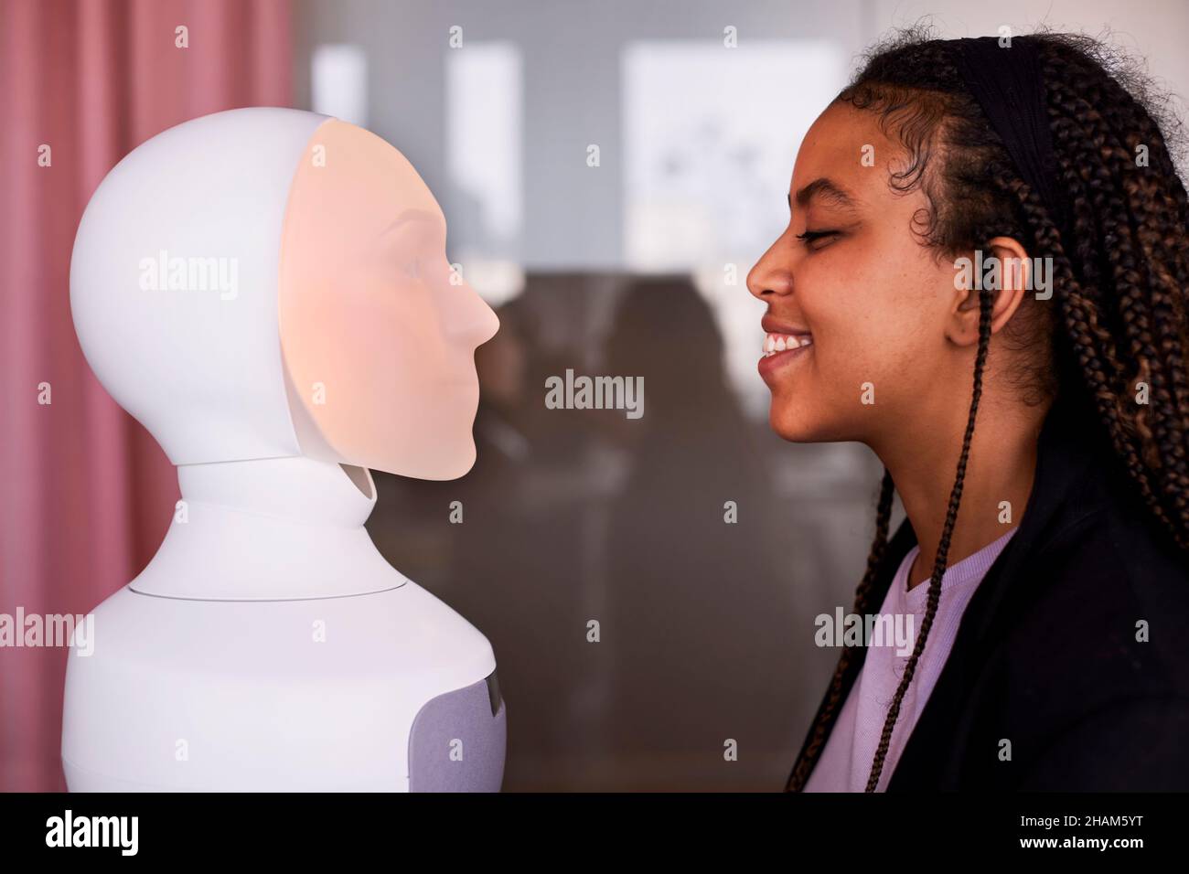 Young woman looking at robot voice assistant Stock Photo