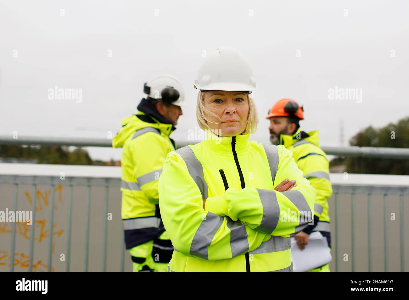 Engineers in reflective clothing standing on bridge Stock Photo