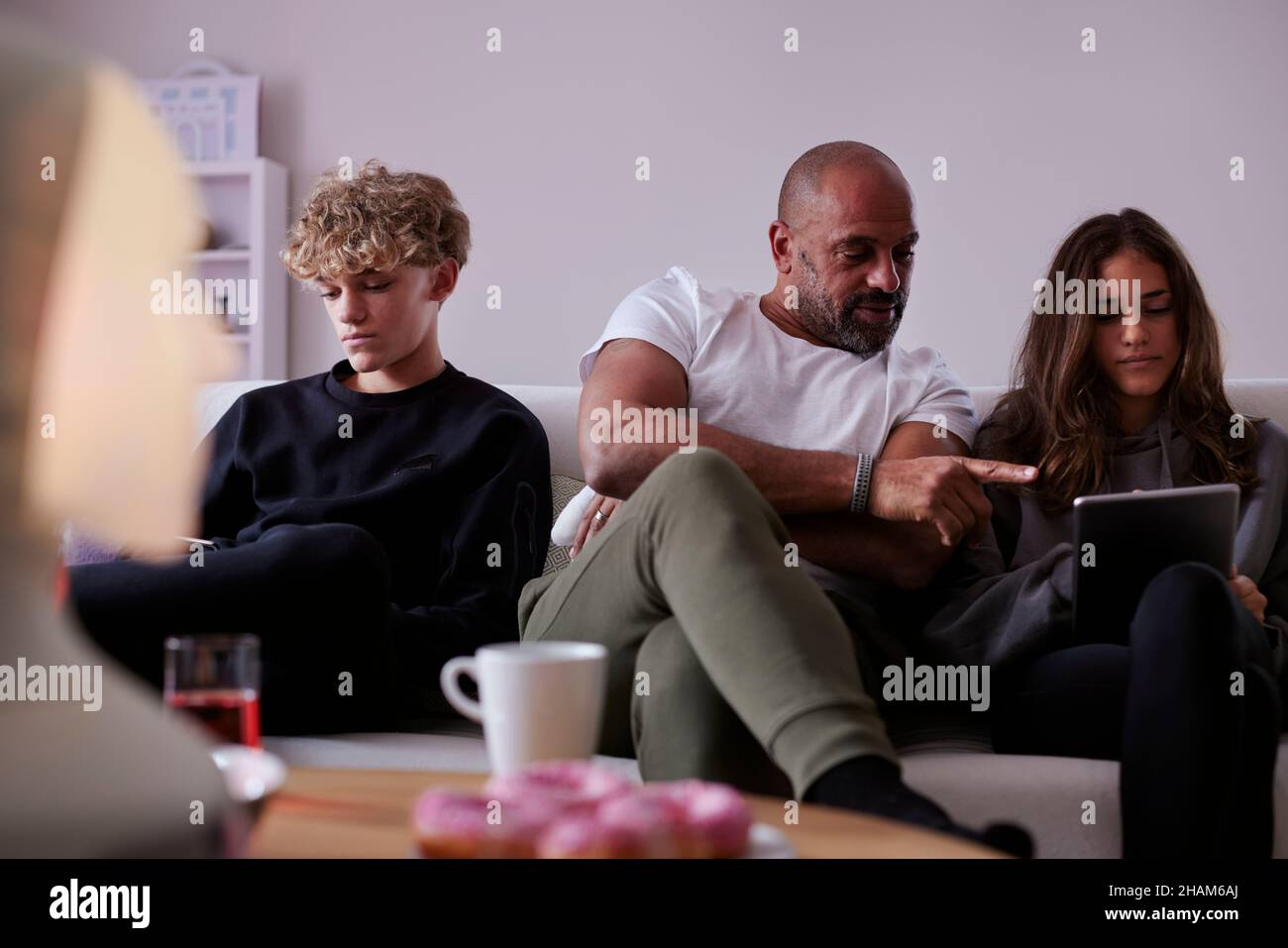 Father with children sitting on sofa and using tablet Stock Photo
