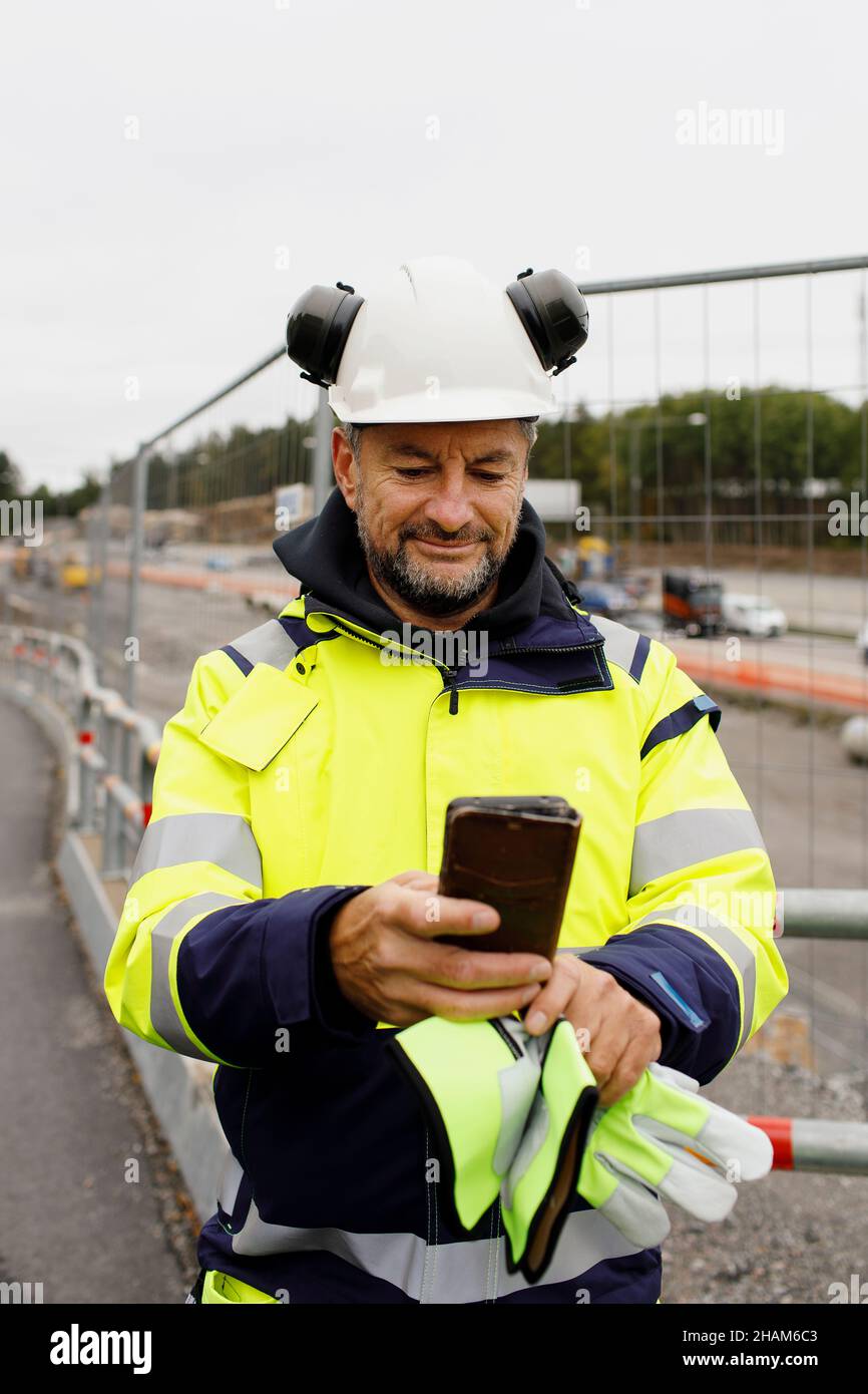 Male engineer in reflecting clothing using cell phone Stock Photo