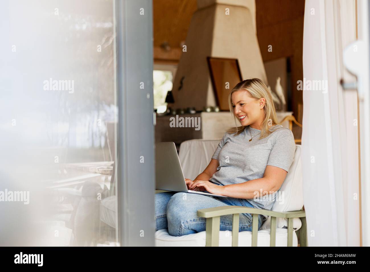Smiling woman using laptop on sofa Stock Photo