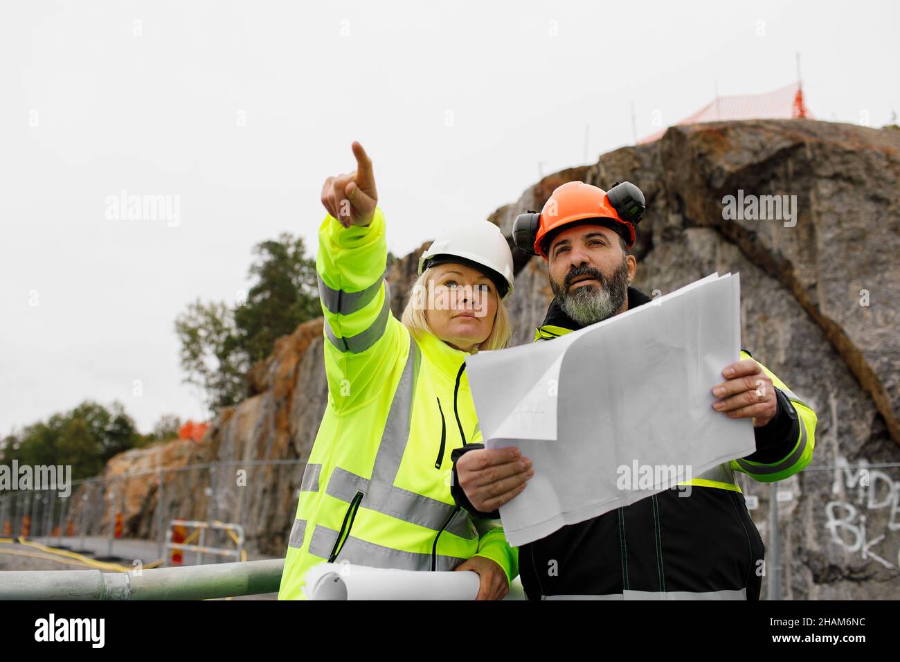 Engineers in reflecting clothing looking at blueprints Stock Photo