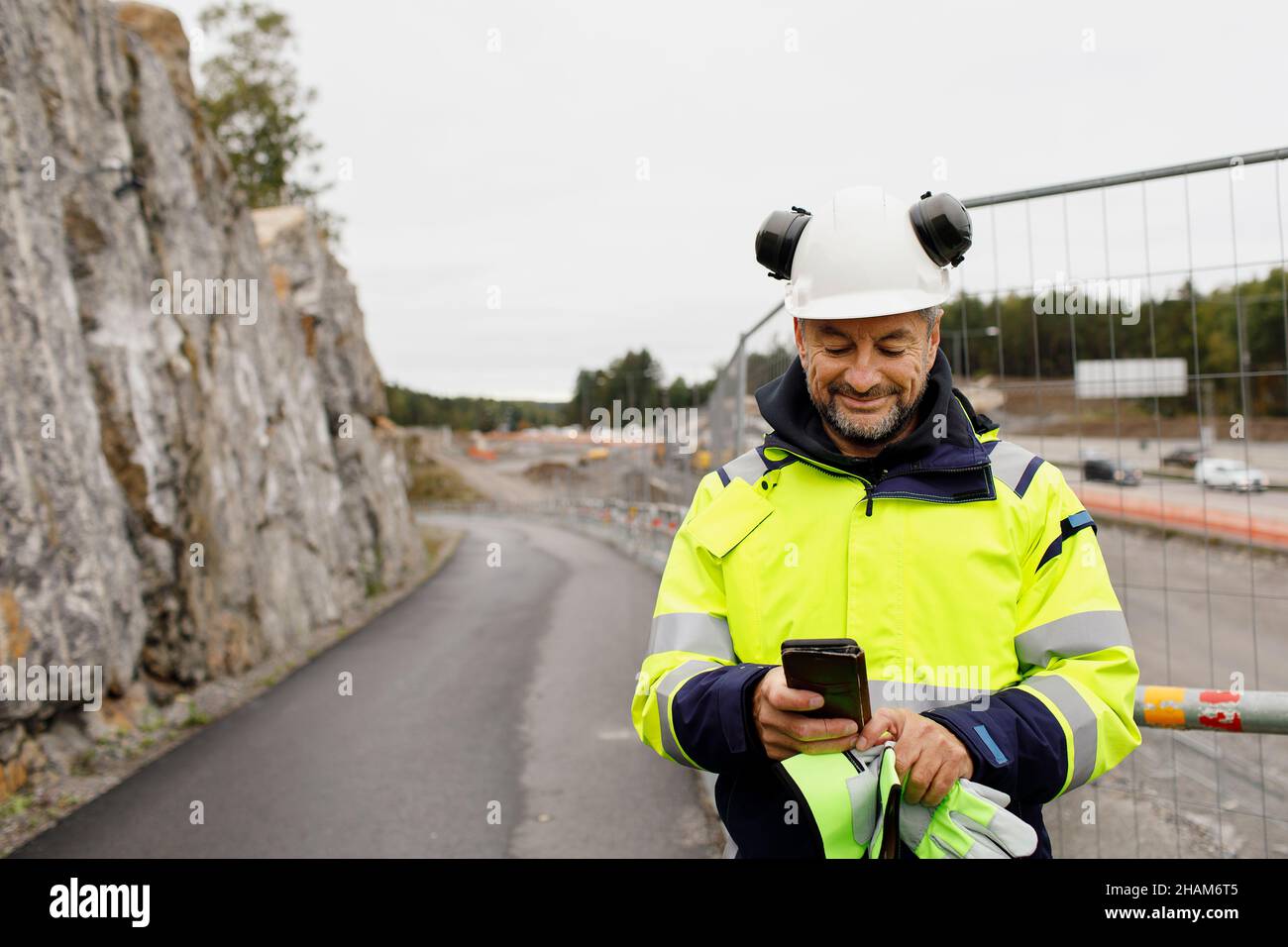 Male engineer in reflecting clothing using cell phone Stock Photo