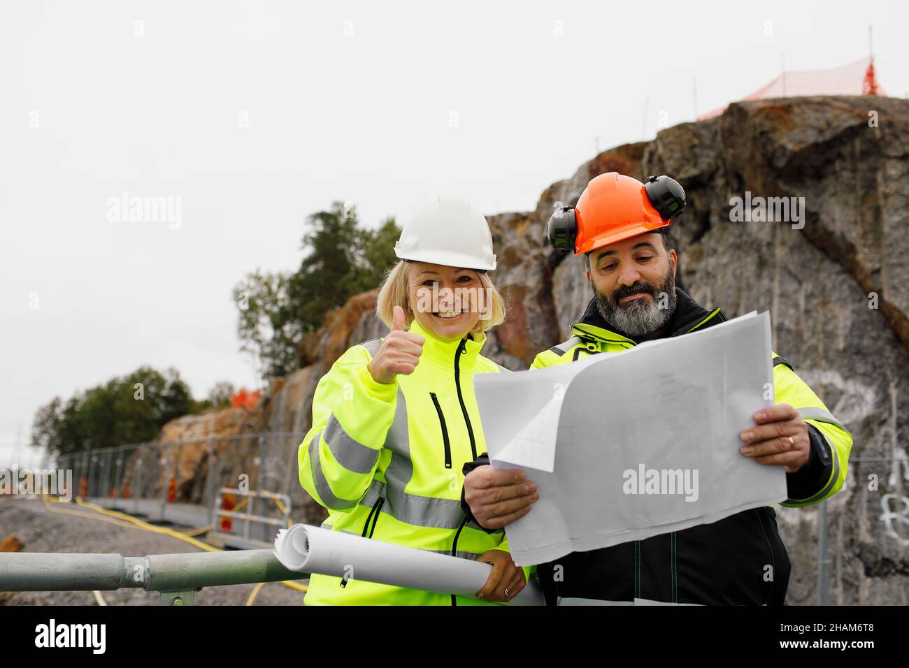 Engineers in reflecting clothing looking at blueprints Stock Photo
