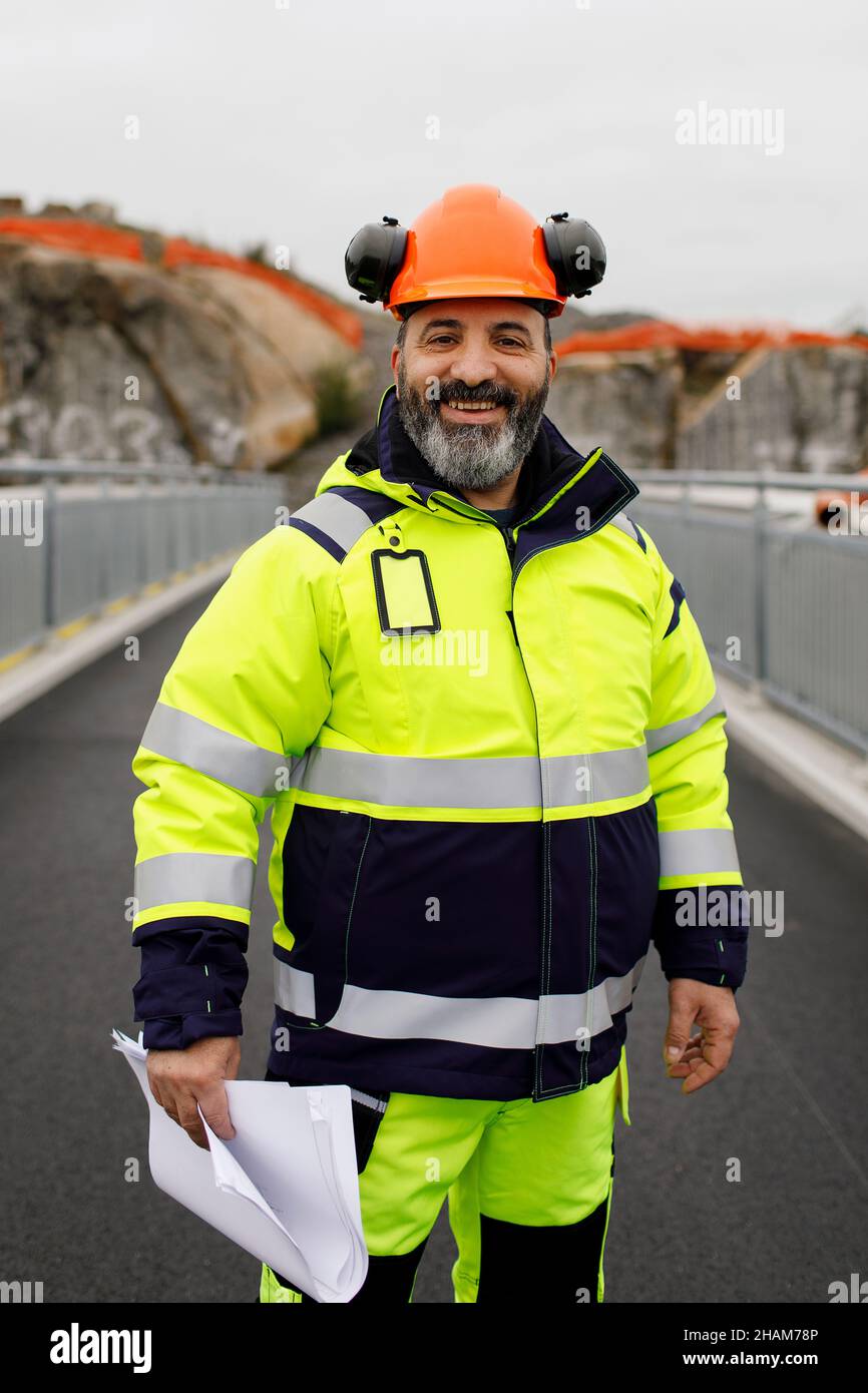 Portrait of male engineer in reflecting clothing standing on bridge Stock Photo