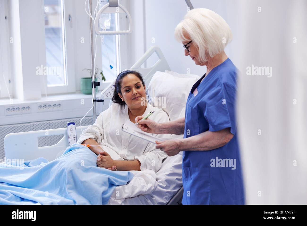 Female patient on hospital bed talking to nurse Stock Photo - Alamy