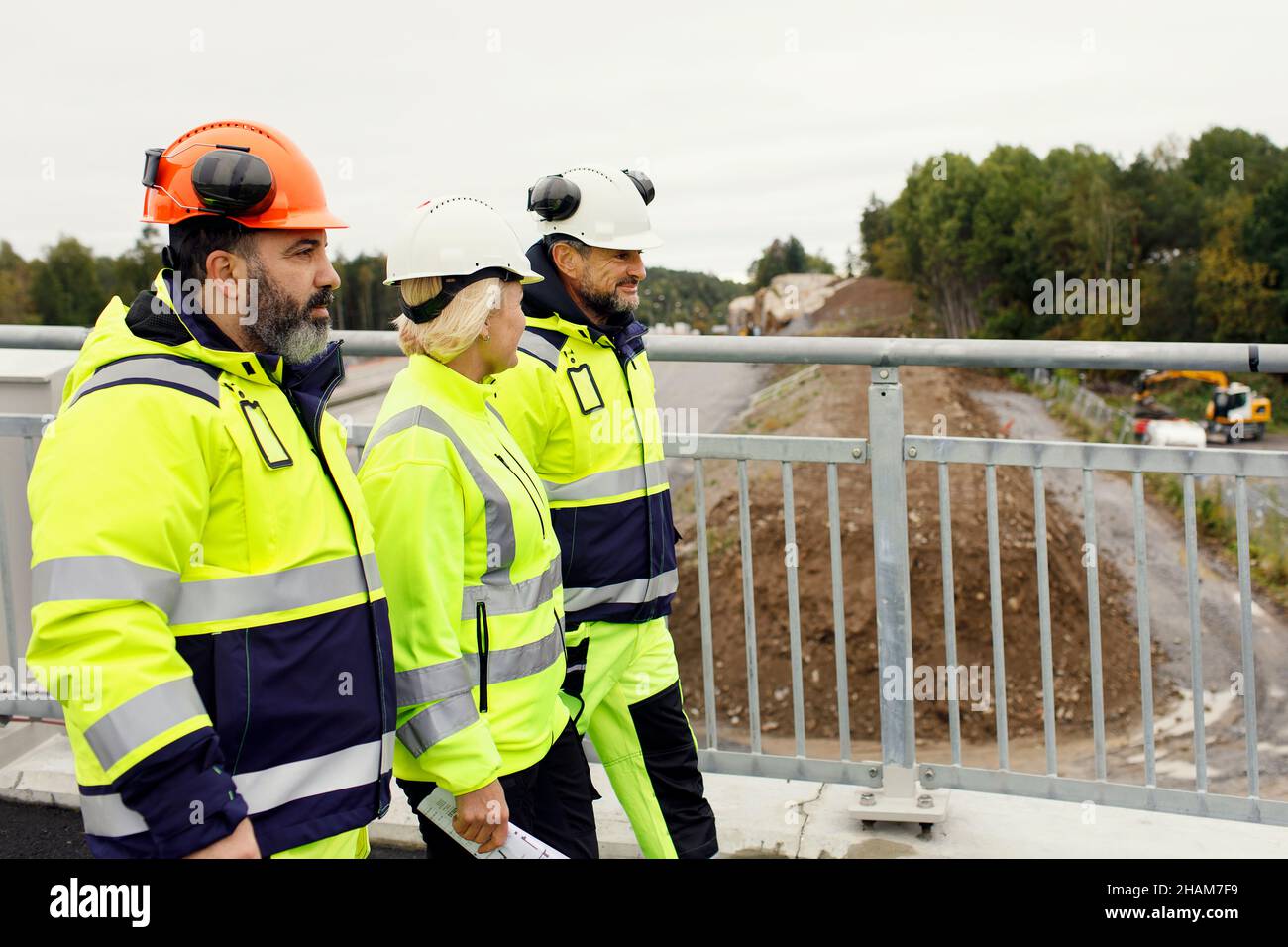 Engineers in reflective clothing walking on bridge Stock Photo