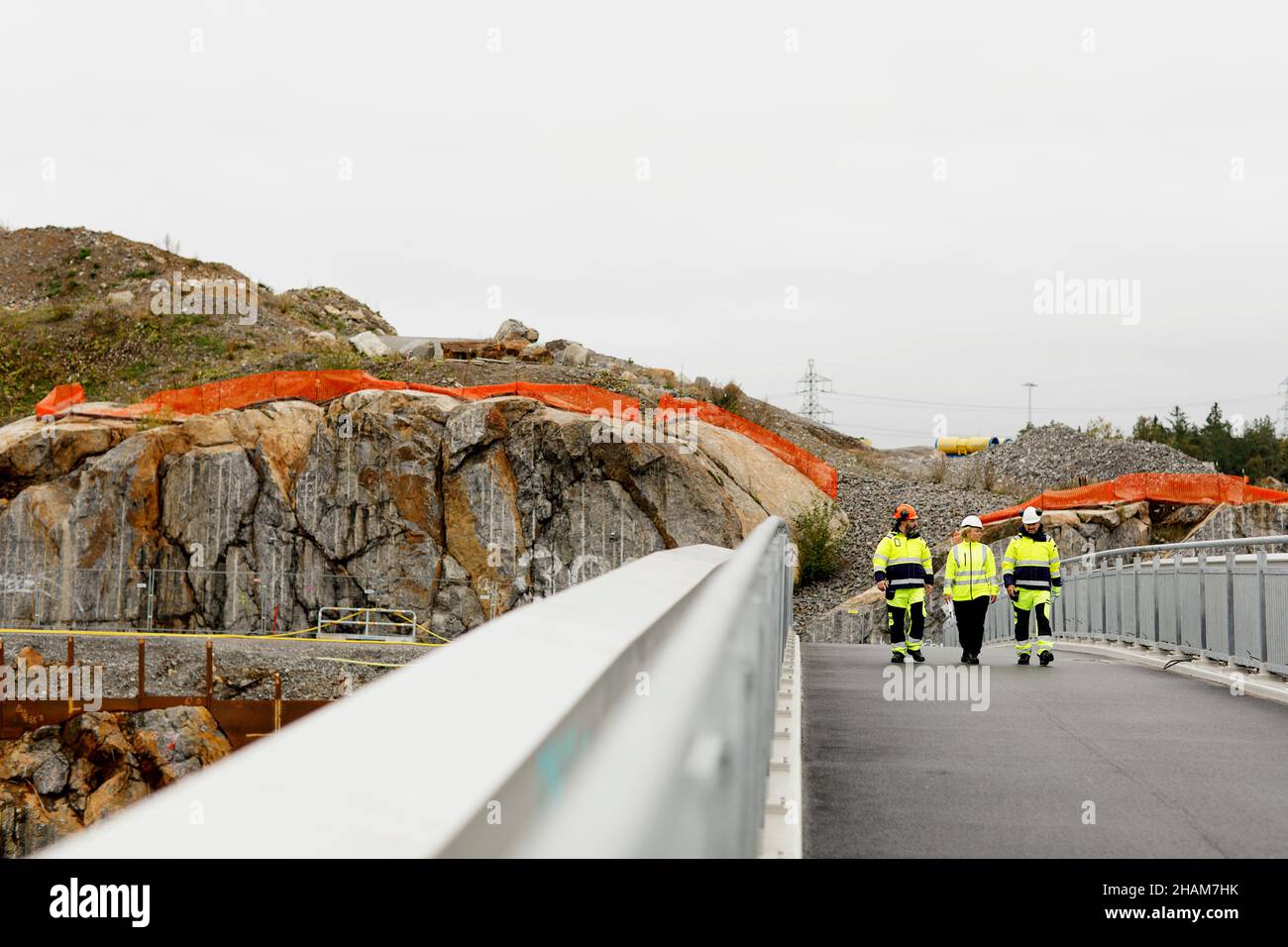 Engineers in reflective clothing walking on bridge Stock Photo