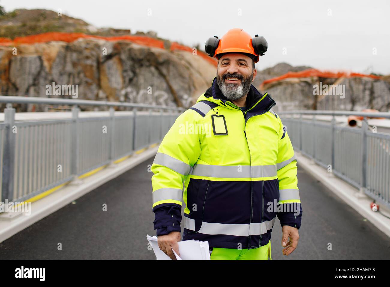 Portrait of male engineer in reflecting clothing standing on bridge Stock Photo