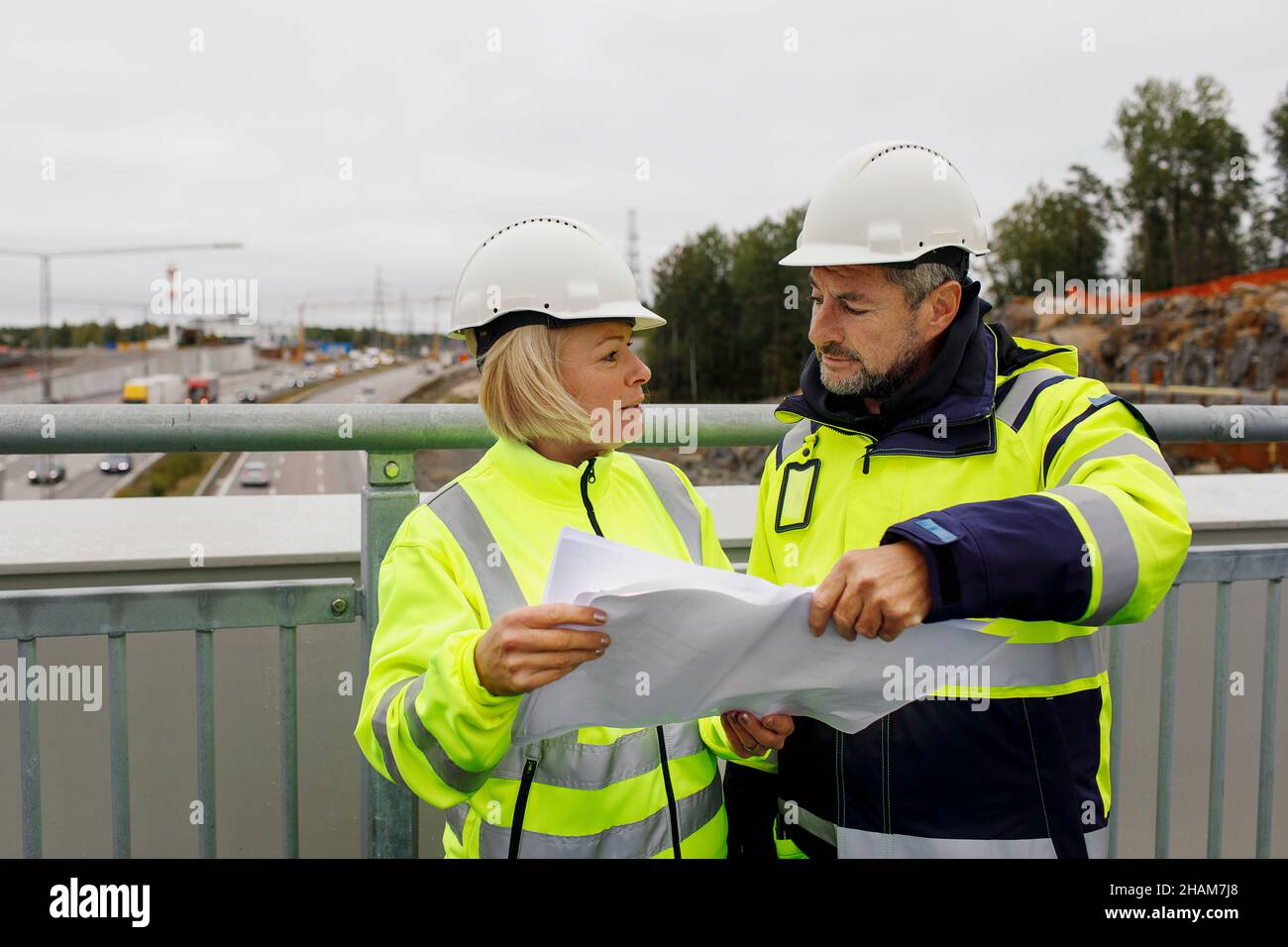 Engineers in reflecting clothing looking at blueprints Stock Photo