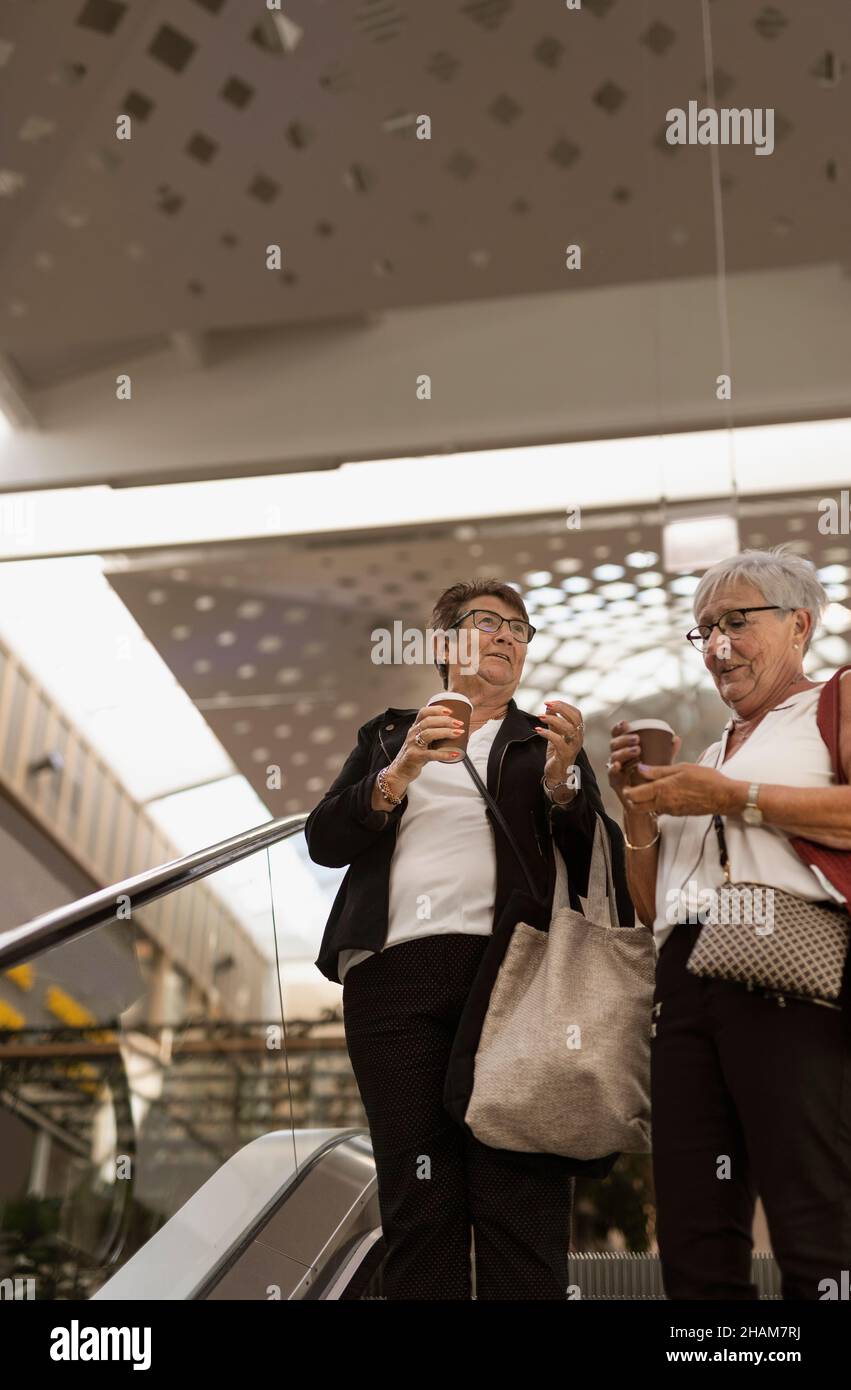 Smiling women on escalator Stock Photo