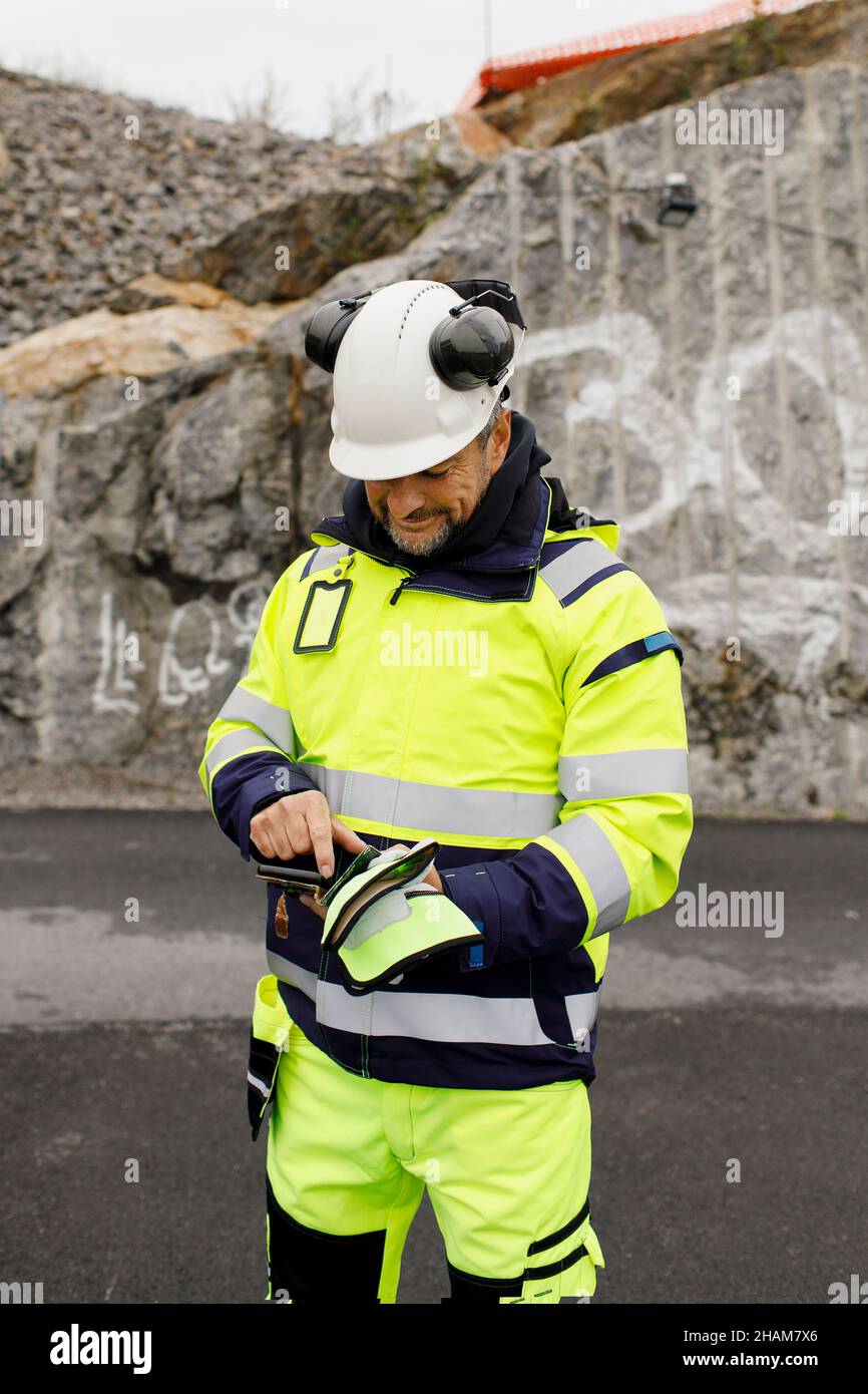 Male engineer in reflecting clothing using cell phone Stock Photo