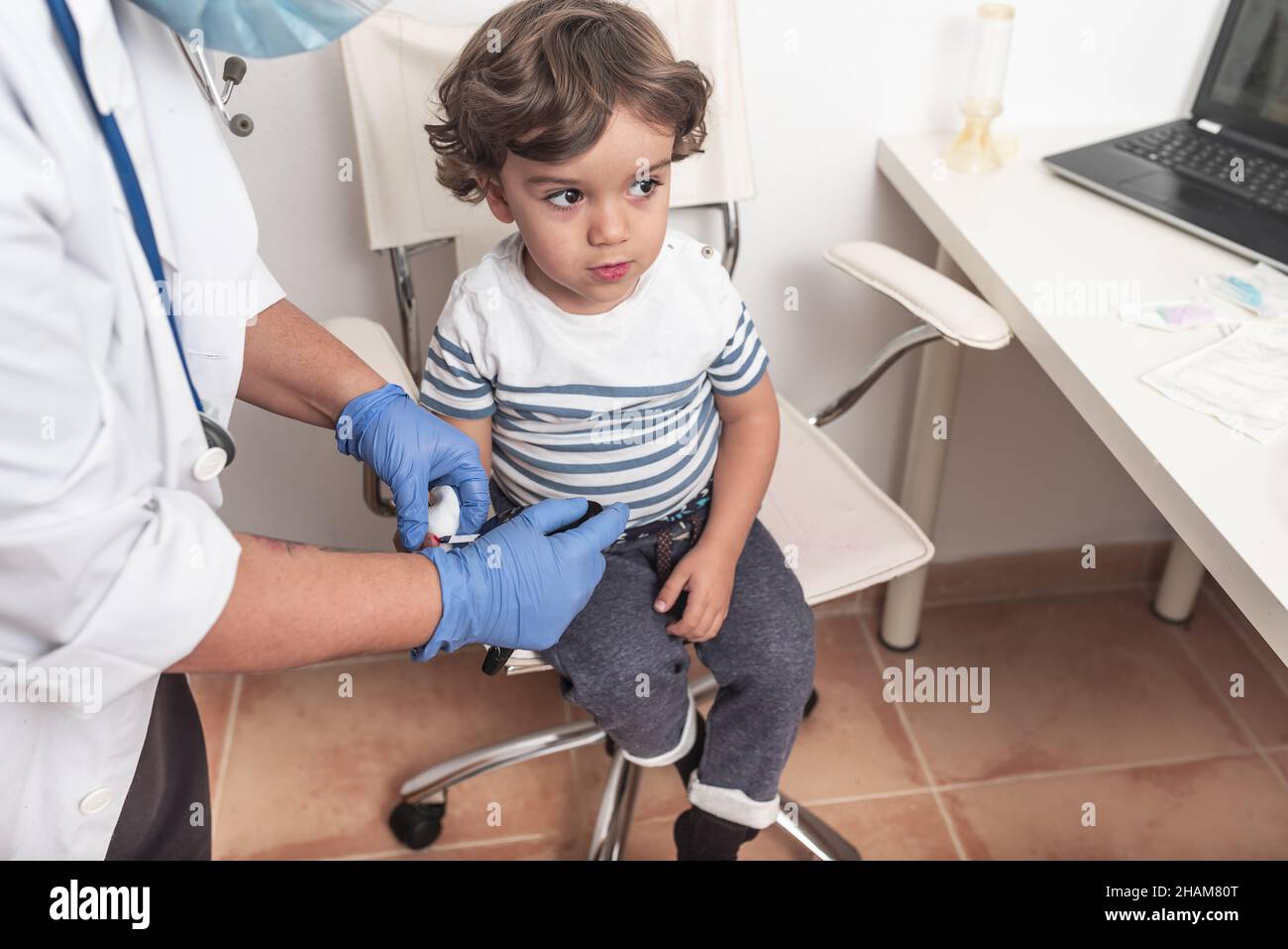 Paediatrician takes blood sample from toddler to check glucose levels ...