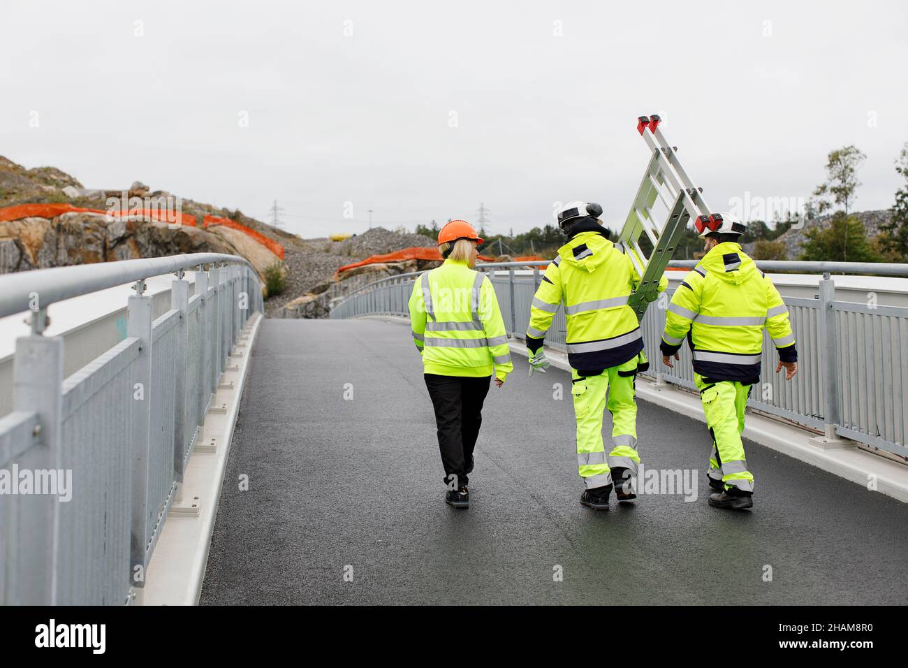 Engineers in reflective clothing walking on bridge Stock Photo Alamy