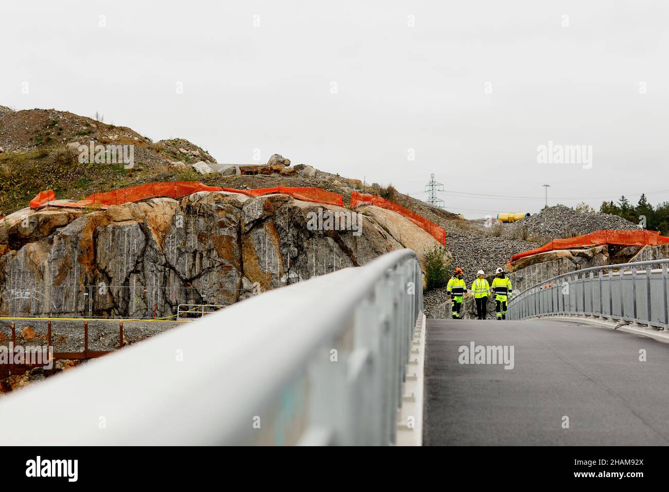 Engineers in reflective clothing walking on bridge Stock Photo