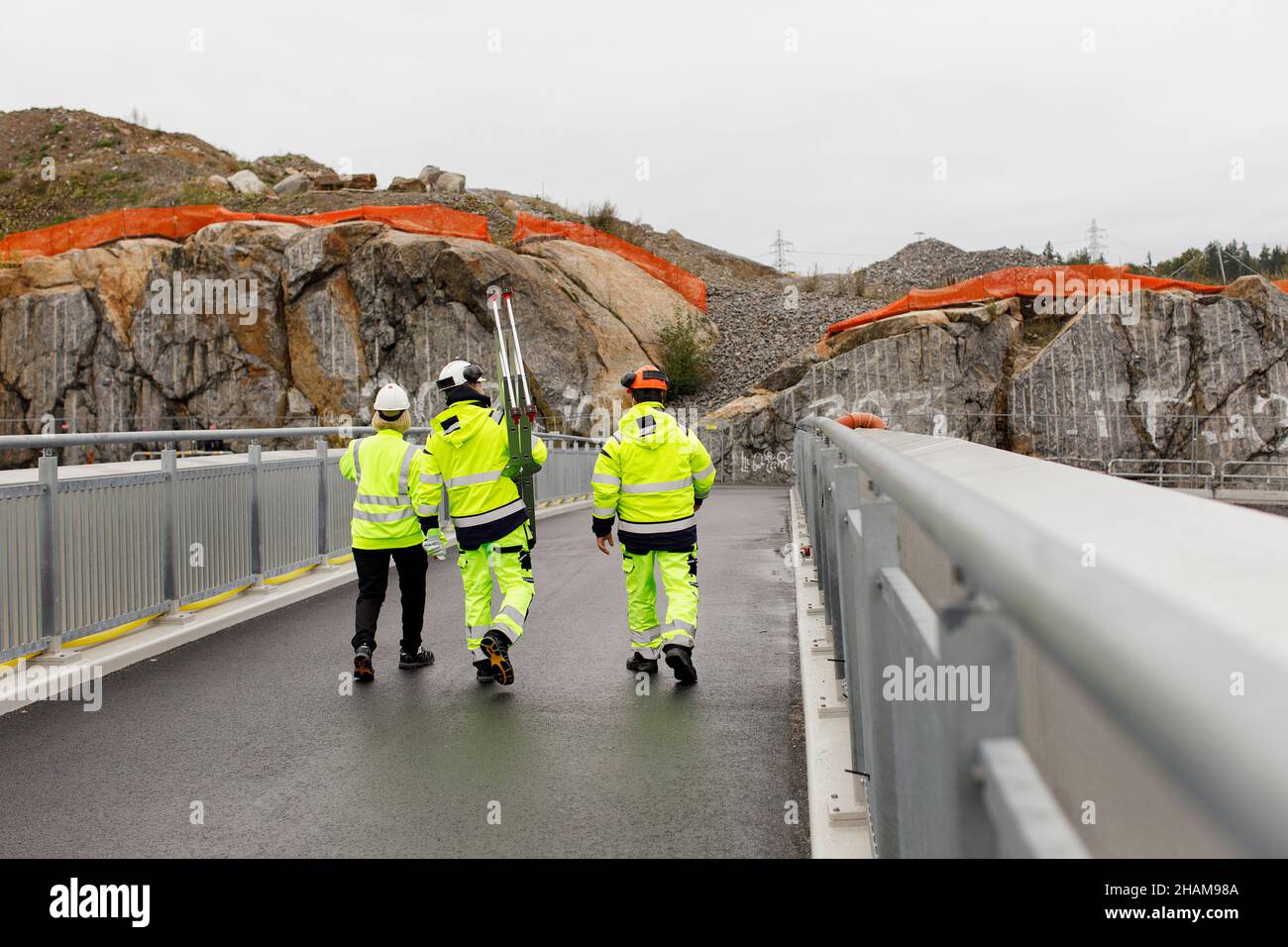 Engineers in reflective clothing walking on bridge Stock Photo