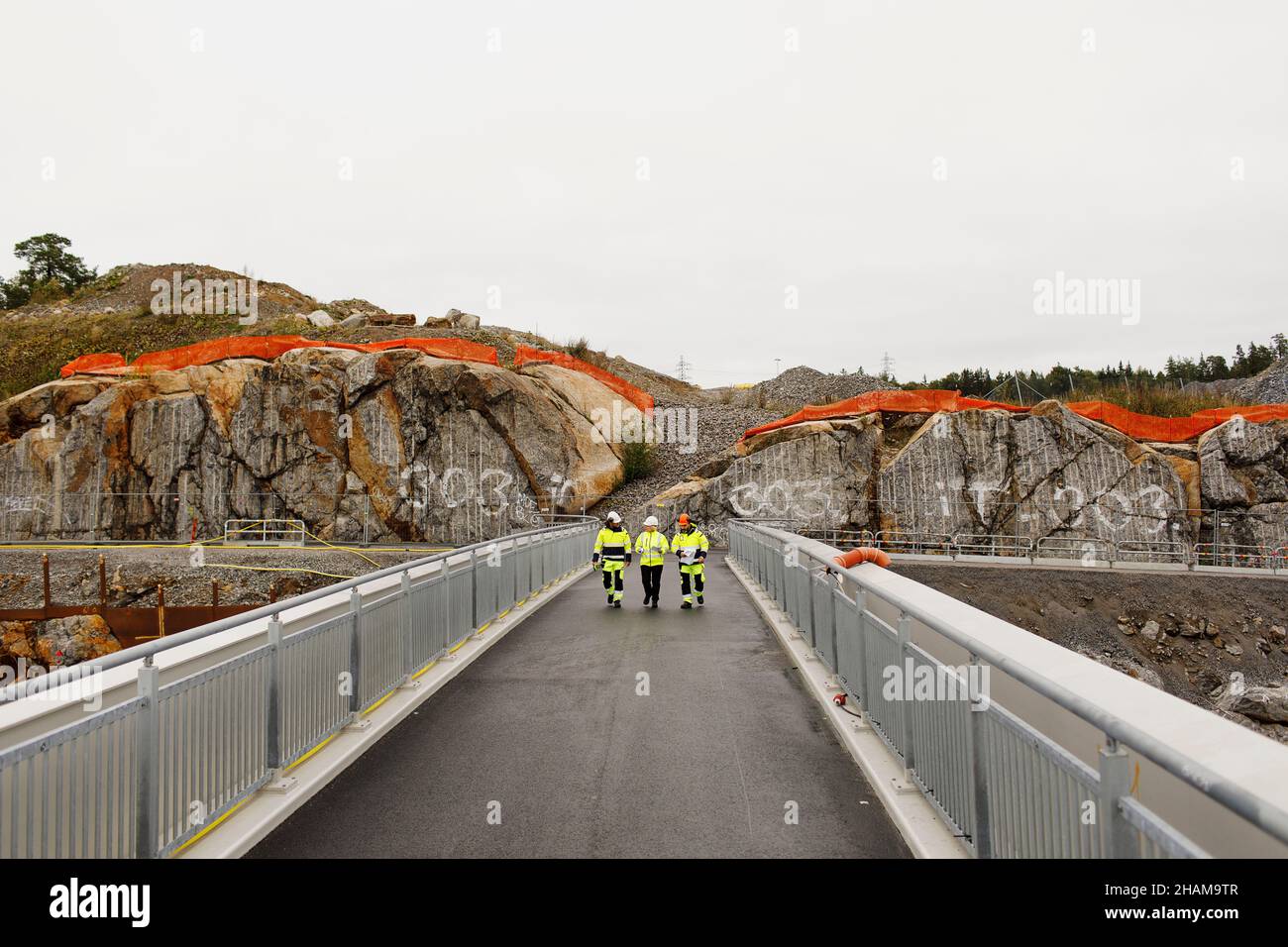 Engineers in reflective clothing walking on bridge Stock Photo