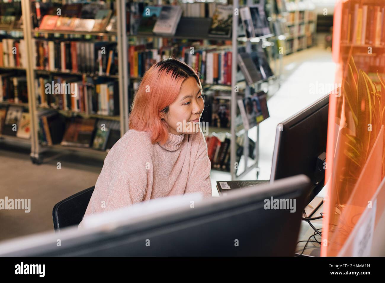 Woman using computer in library Stock Photo - Alamy