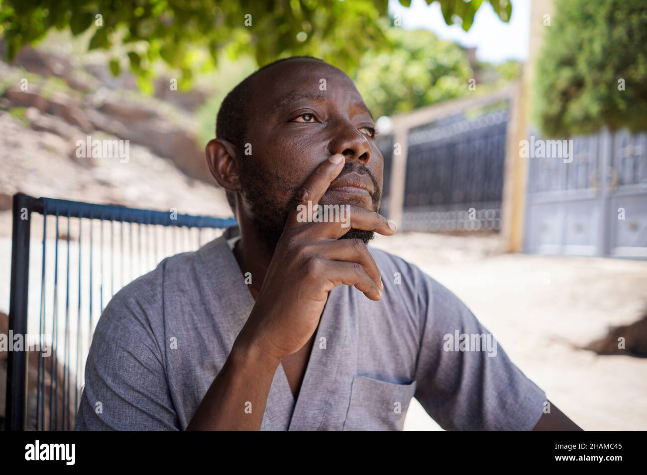 Close up portrait of thoughtful african male man sit and look analyzing outdoors Stock Photo
