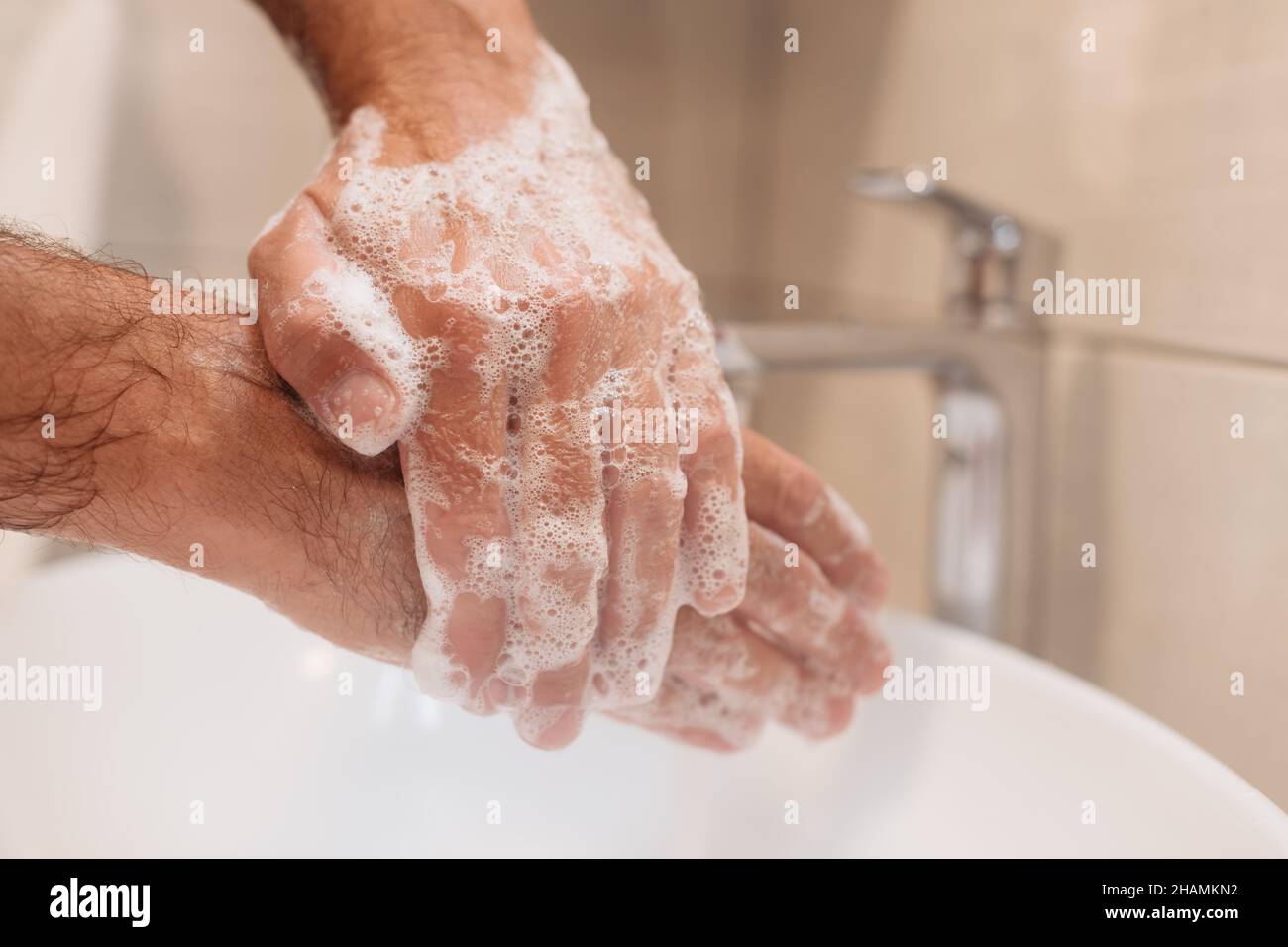 Close up of male washing hands with soap in bathroom, selective focus Stock Photo